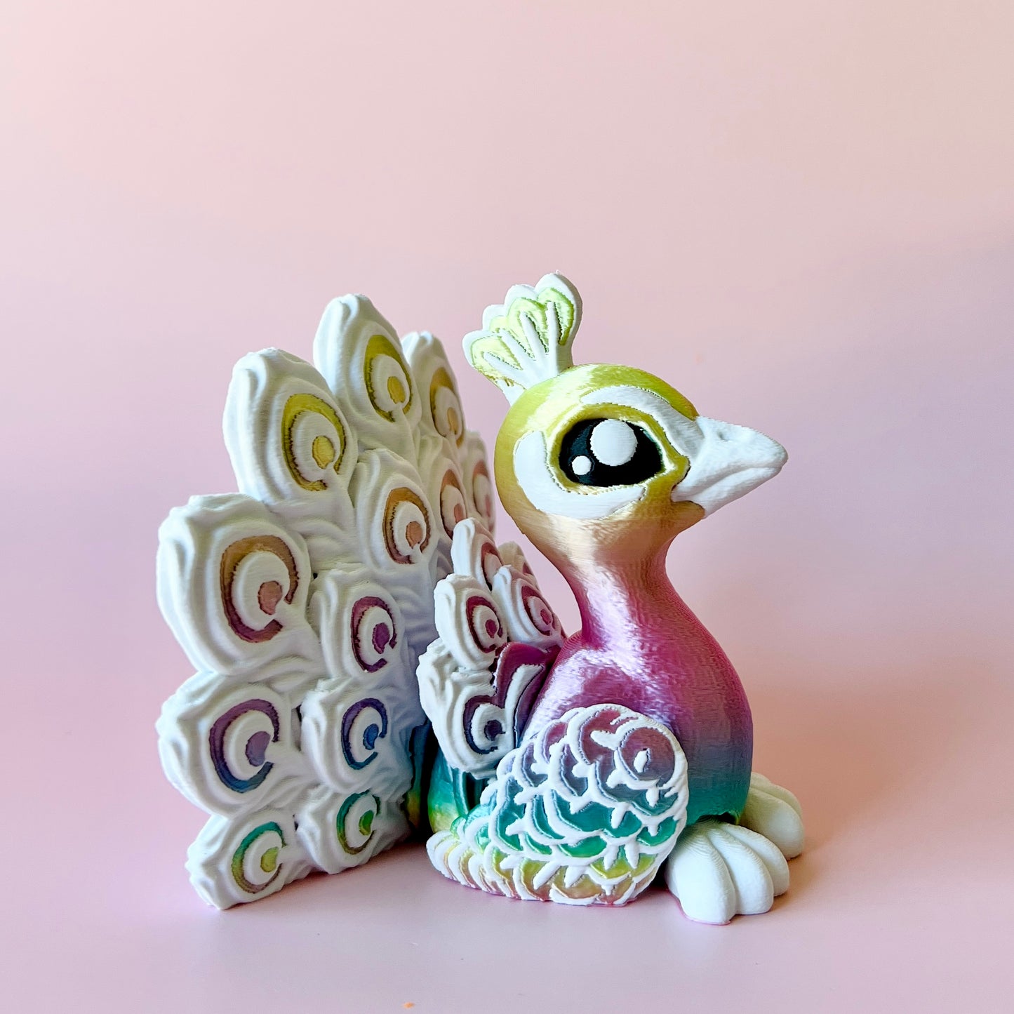 Colorful peacock figurine with intricate feather patterns, set against a soft pink background.