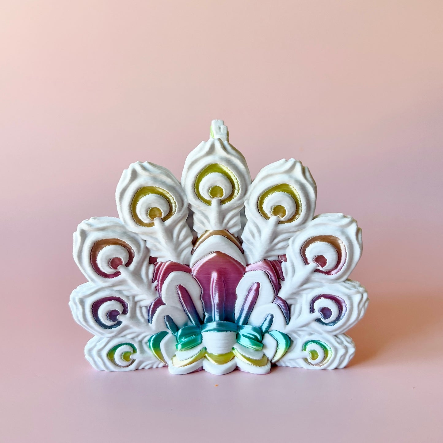Colorful peacock feather display with intricate details against a soft pink background.