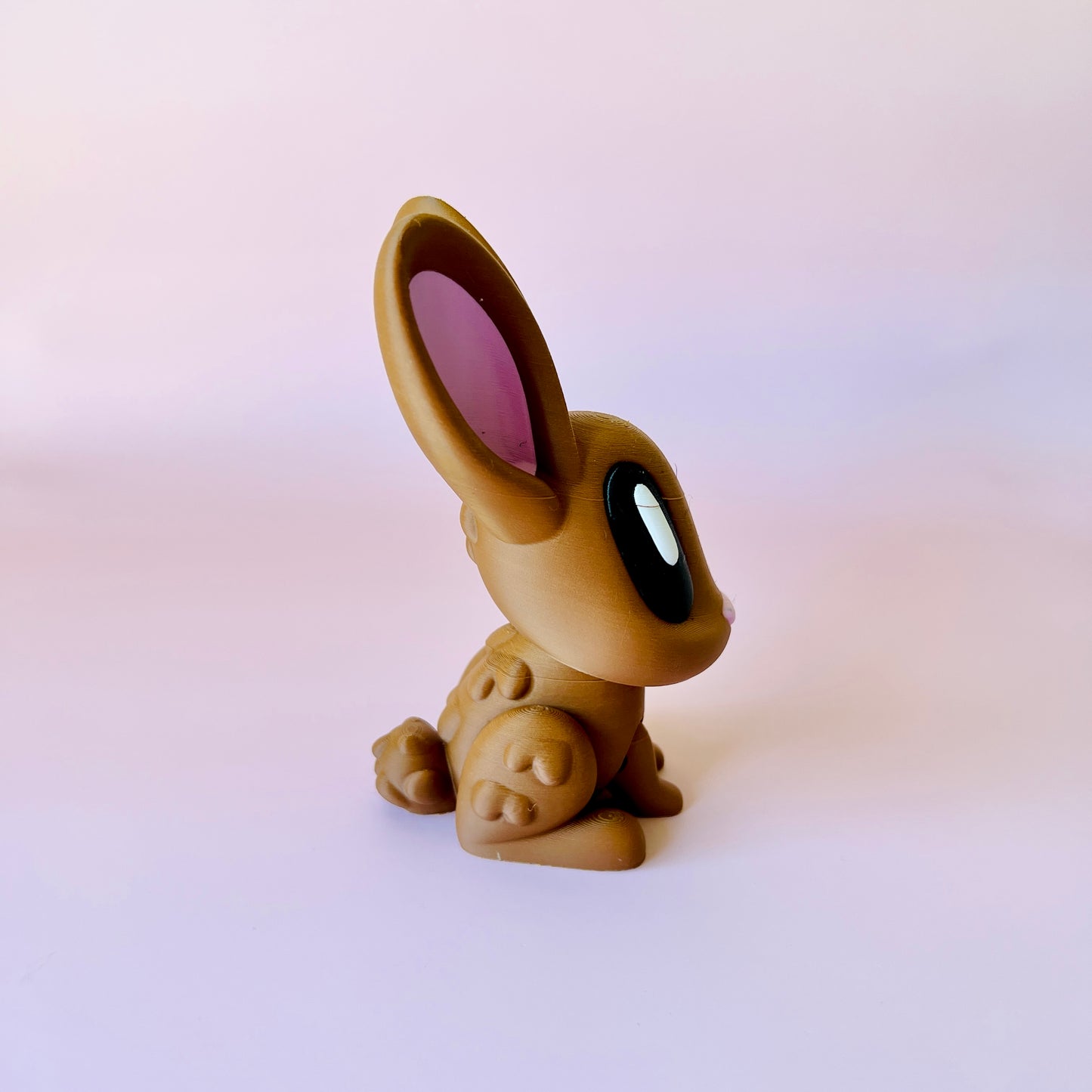 A stylized rabbit figure with large eyes and pink-tinted ears sits against a soft pink background.