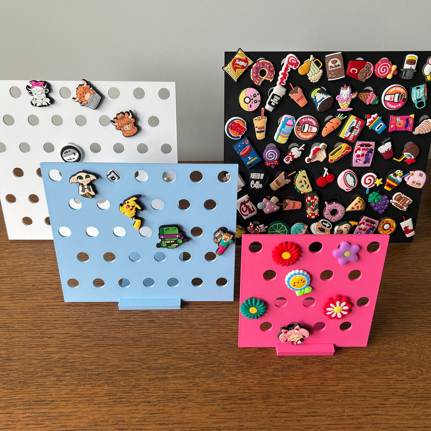 Colorful 3D-printed stands showcase a variety of fun charms against a neutral backdrop, enhancing collection display.
