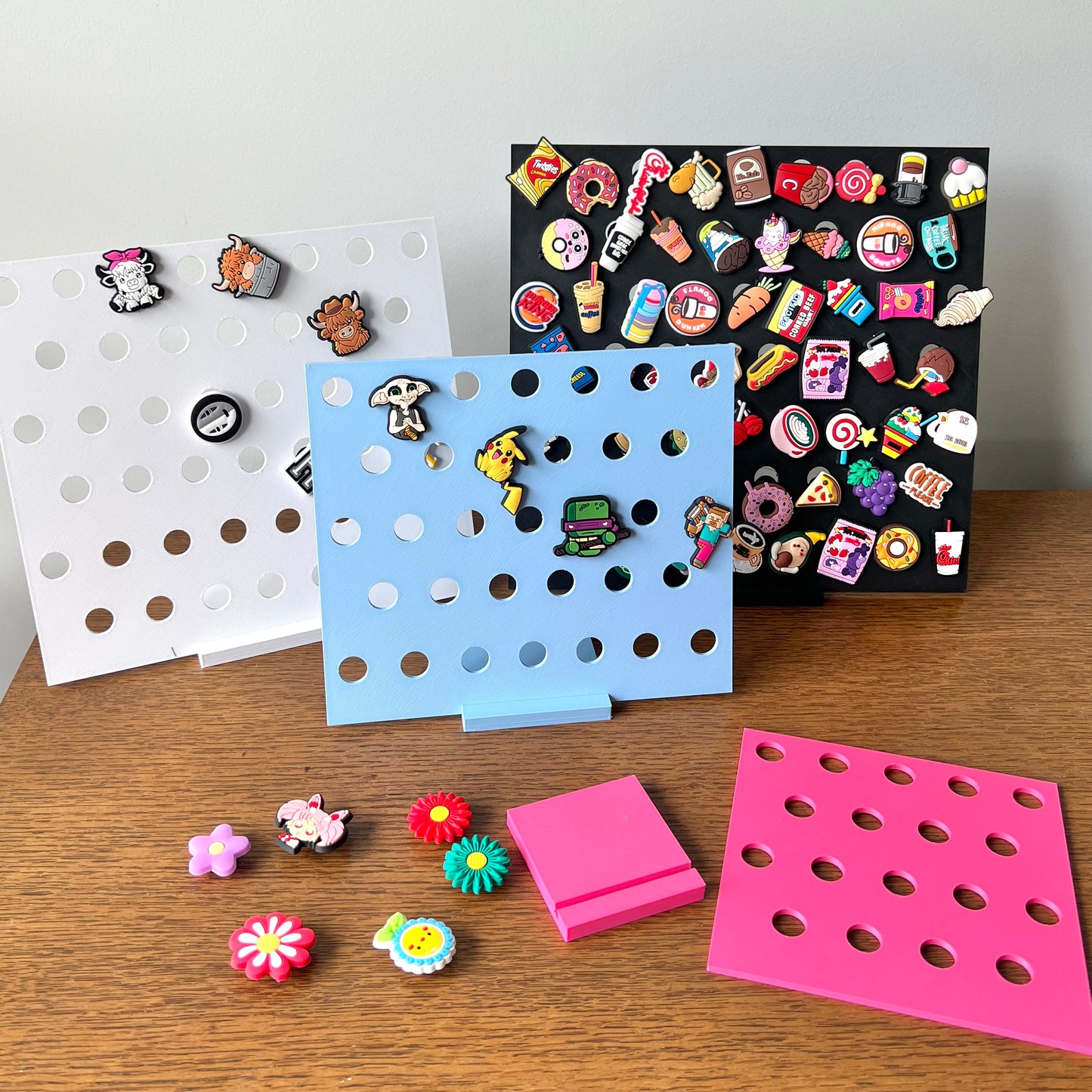 Colorful 3D-printed display stands showcasing various charms against a wooden surface, emphasizing style and organization.