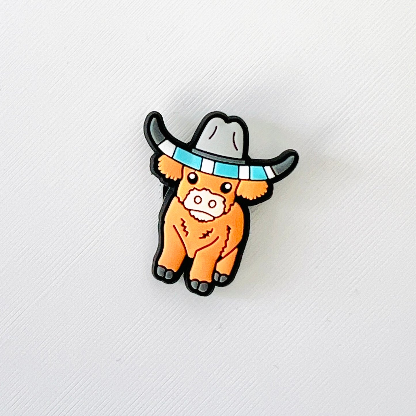 Adorable brown Highland cow wearing a cowboy hat, perfect for adding a fun western touch to your favorite shoes.