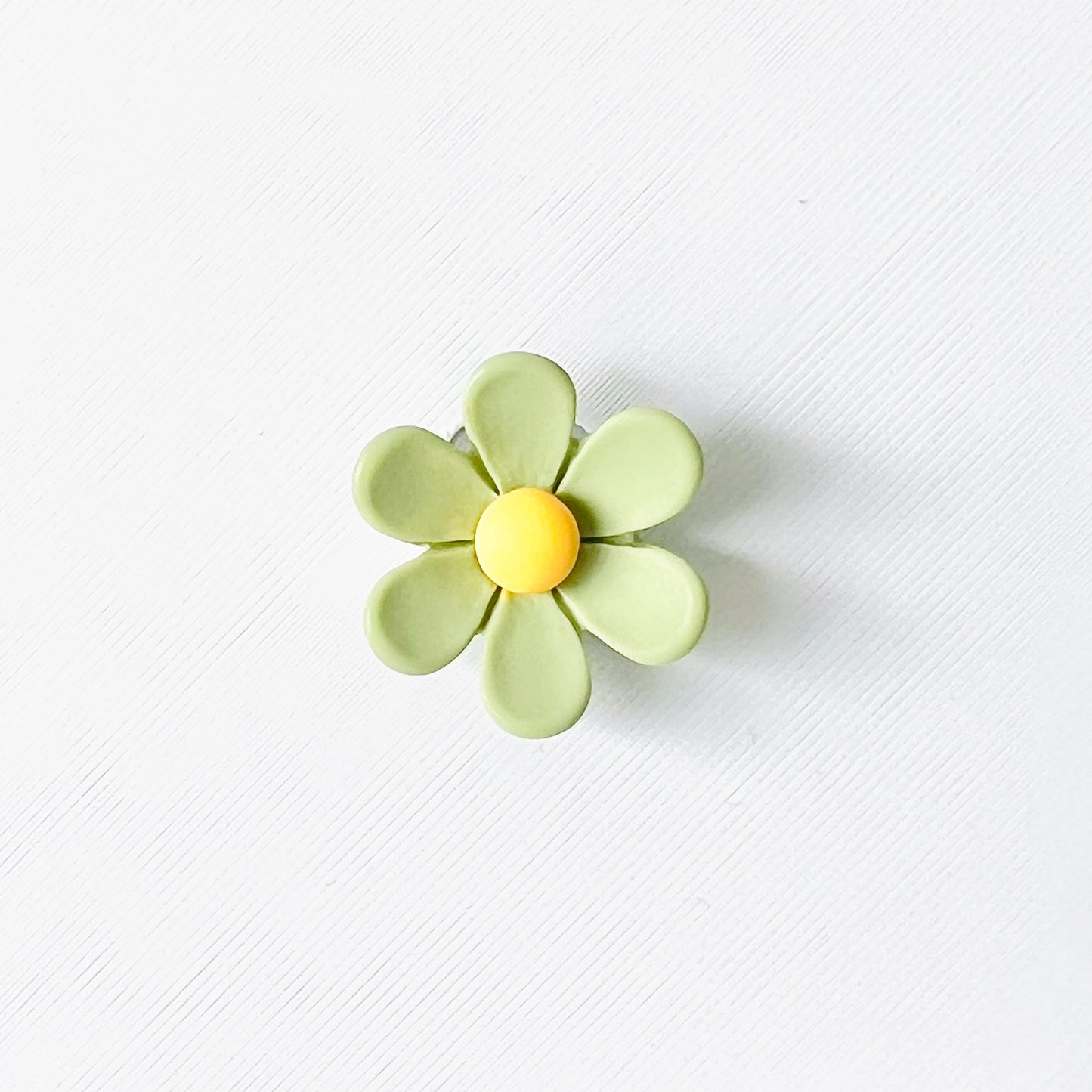 Cheerful green flower charm with yellow center, perfect for adding a nature-inspired touch to your footwear.