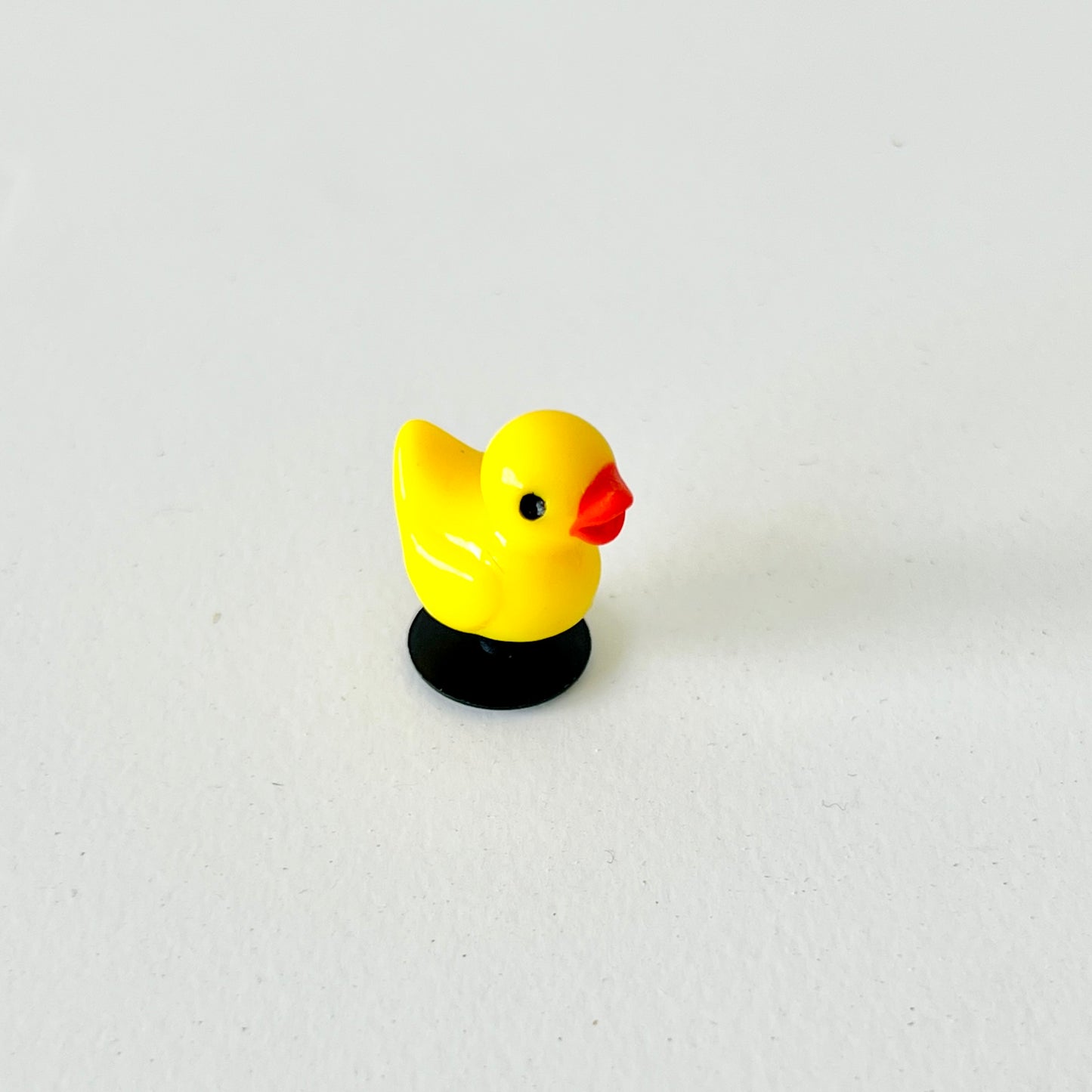 Bright yellow duck charm with a cheerful expression, featuring black base and glossy finish, perfect for footwear decoration.