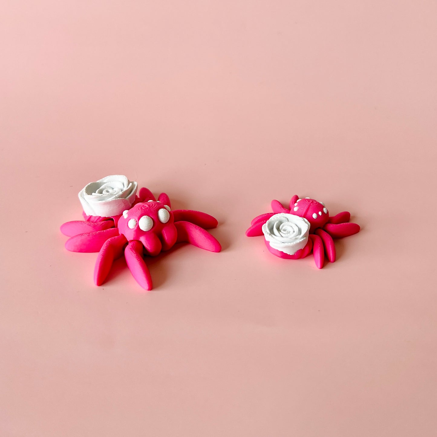 Charming pink spider with delicate white rose, combining whimsy and elegance in a delightful, fidget-sized collectible.