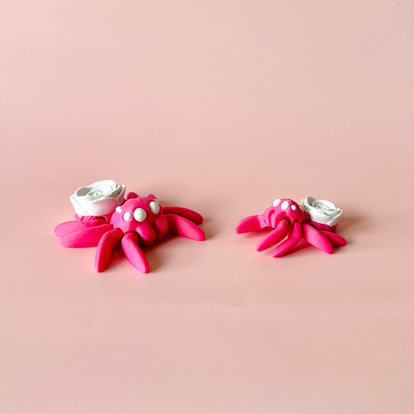 Charming pink spider with a delicate white rose, featuring whimsical details and a playful, elegant design.