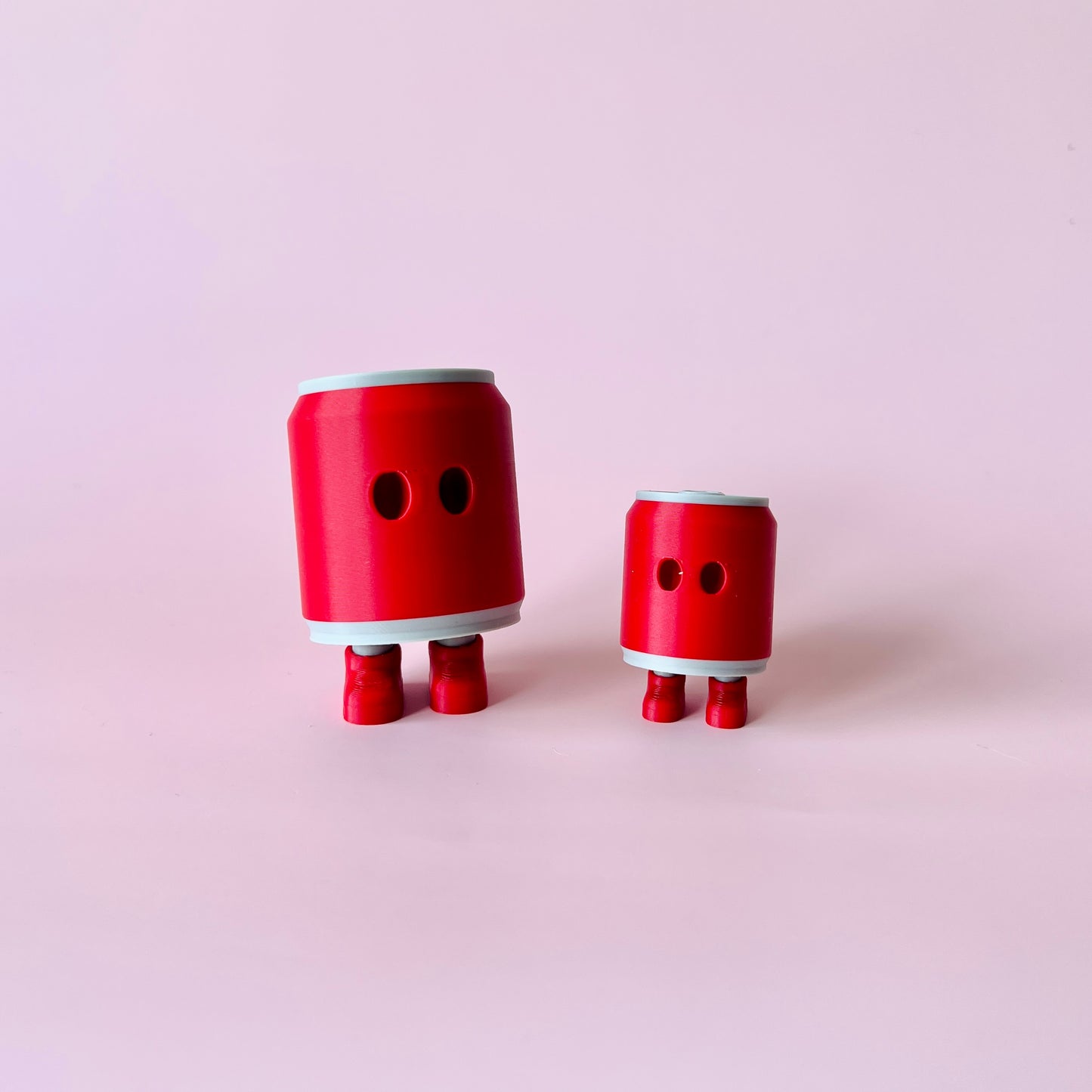 Two red can-shaped figures with legs and eyes stand against a soft pink background.