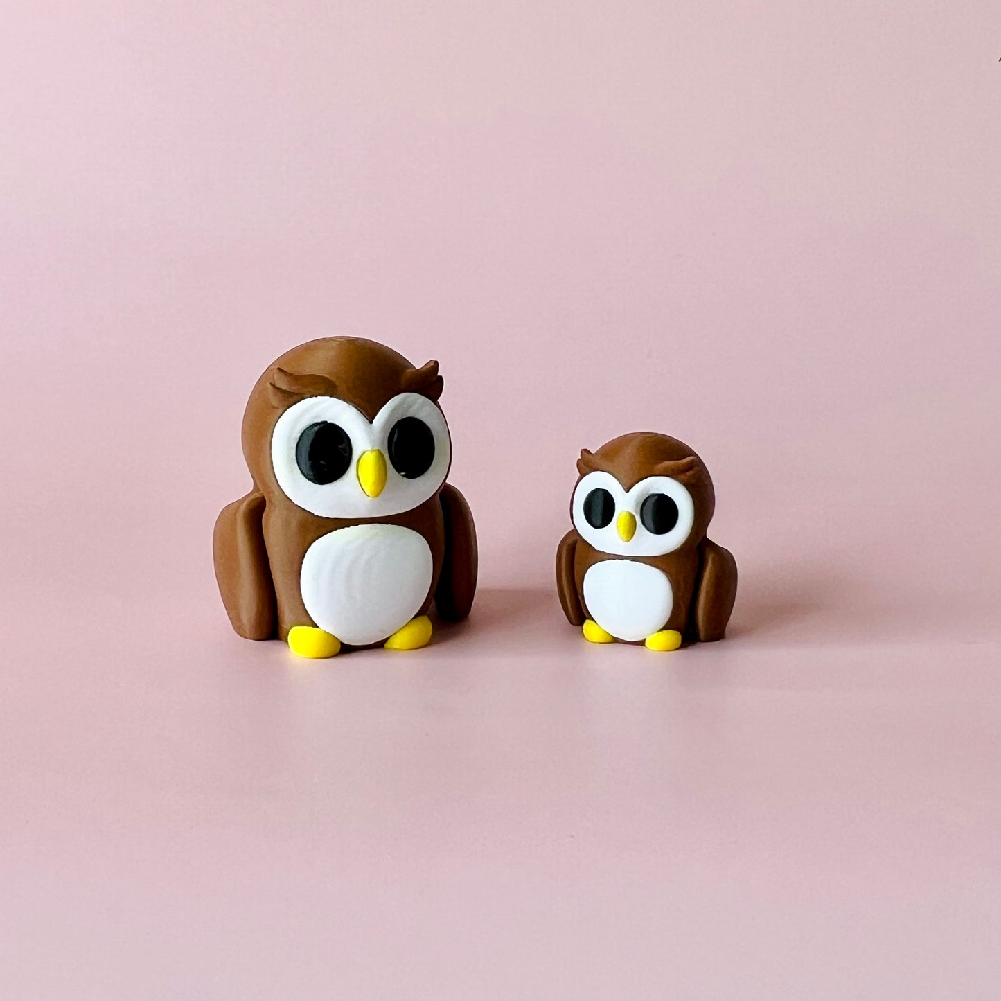 Two charming brown and white owls, one larger and one smaller, set against a soft pink background.