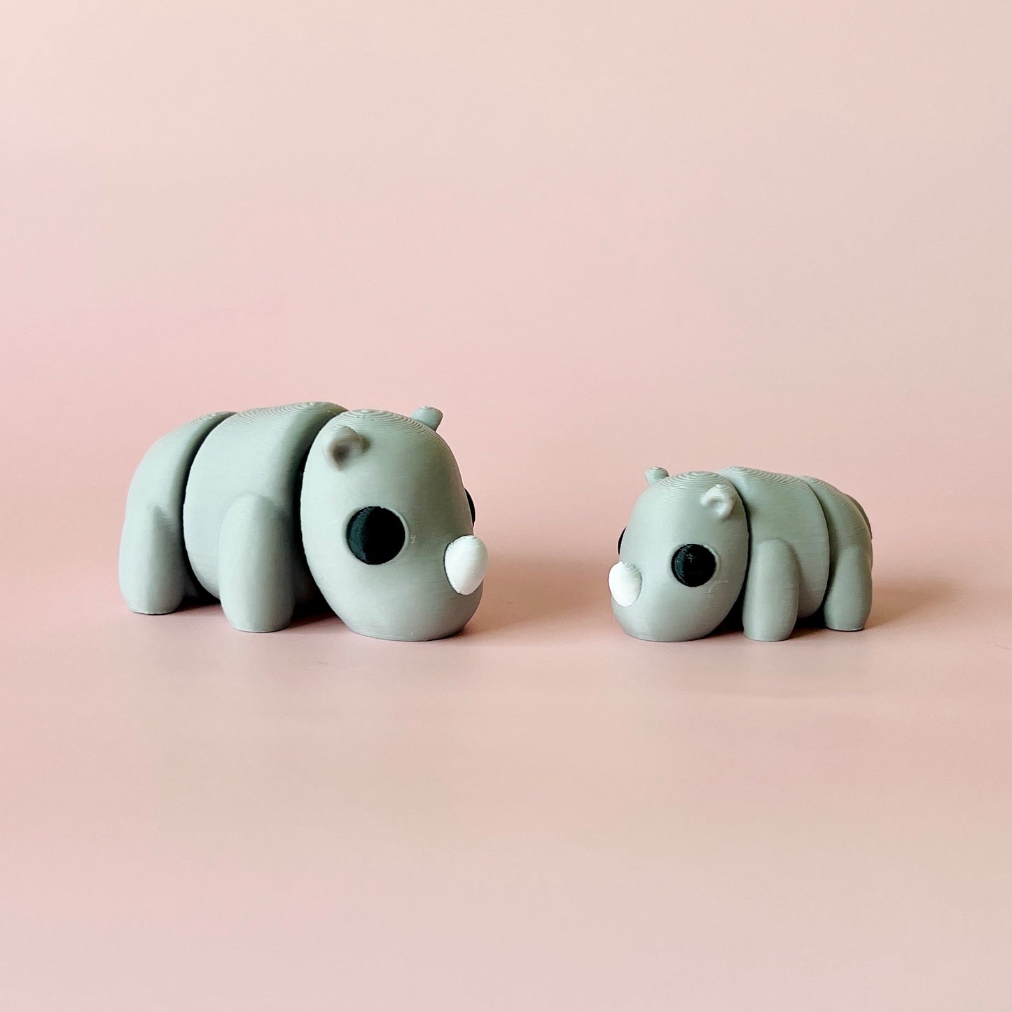Two cute gray figures with black eyes and white noses, set against a soft pink background.