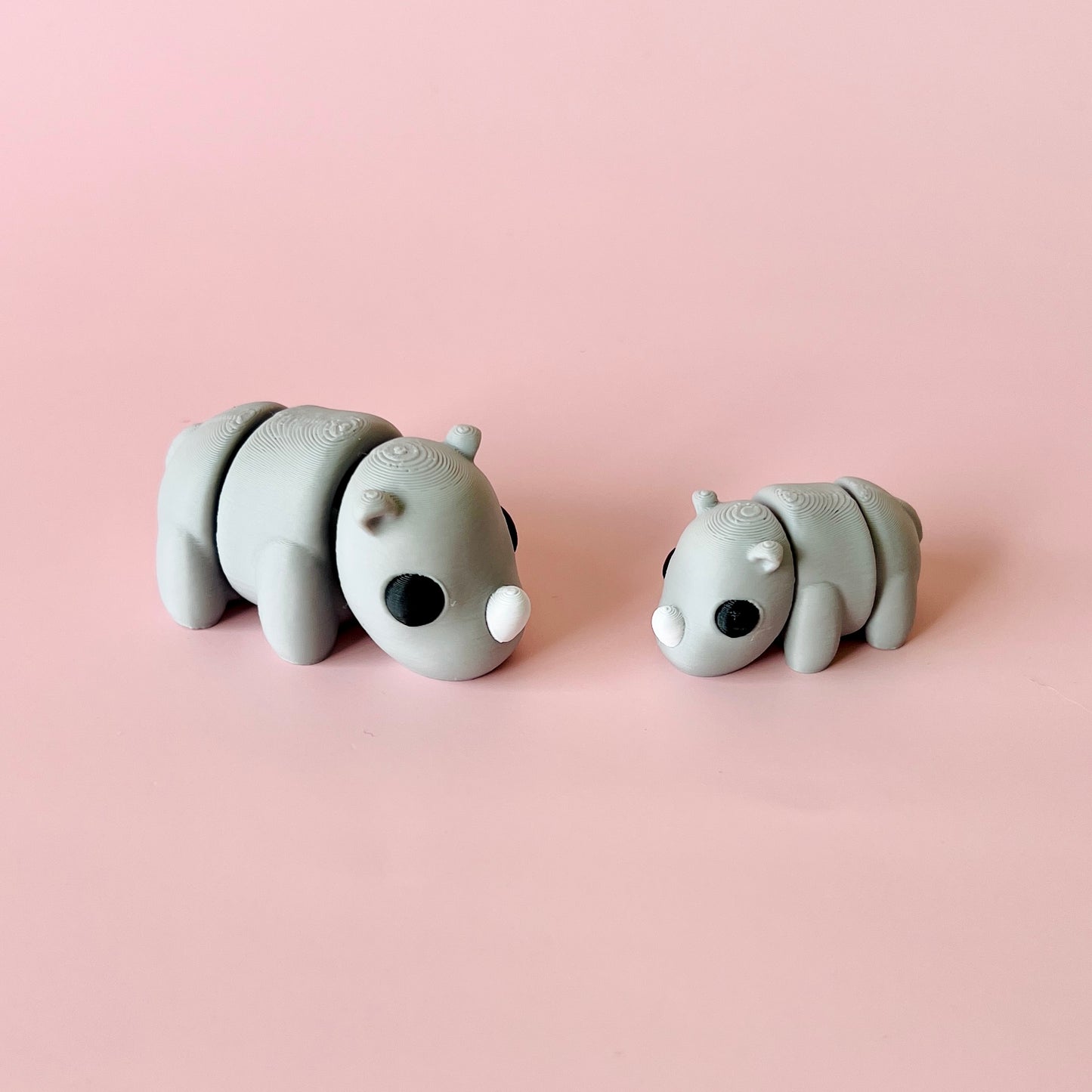 Two gray, stylized figures resembling small animals, set against a soft pink background.