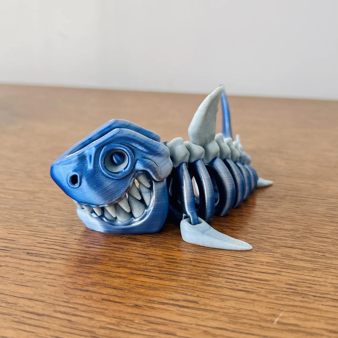 3D-printed skeleton shark figurine in blue and gray, showcasing detailed features and a playful expression.