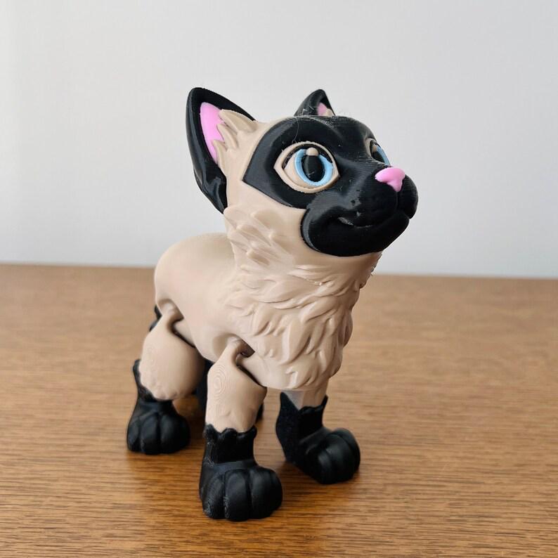 Charming 3D-printed Siamese cat figurine with a sleek design, featuring detailed fur and bright blue eyes.