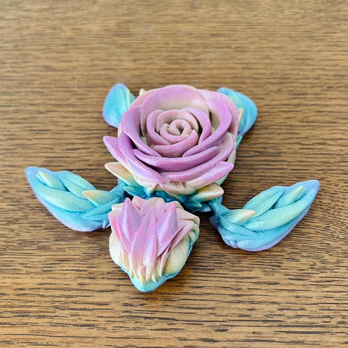 A colorful rose turtle figurine with a blooming rose for a shell, resting on a wooden surface.