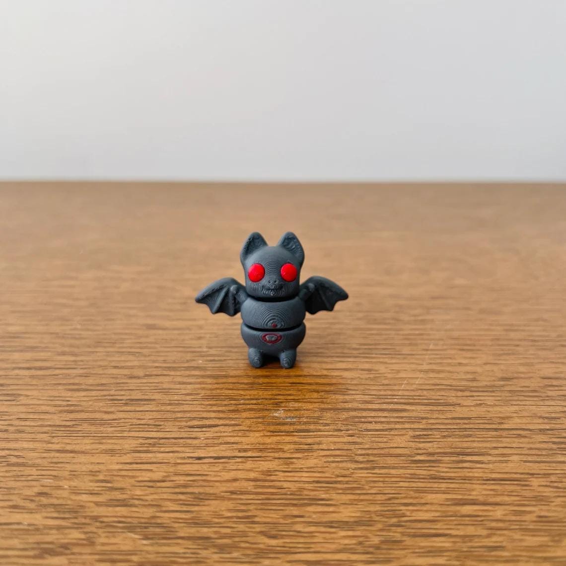 Articulated 3D-printed bat with red eyes and wings, perfect for sensory play and eco-friendly fun.