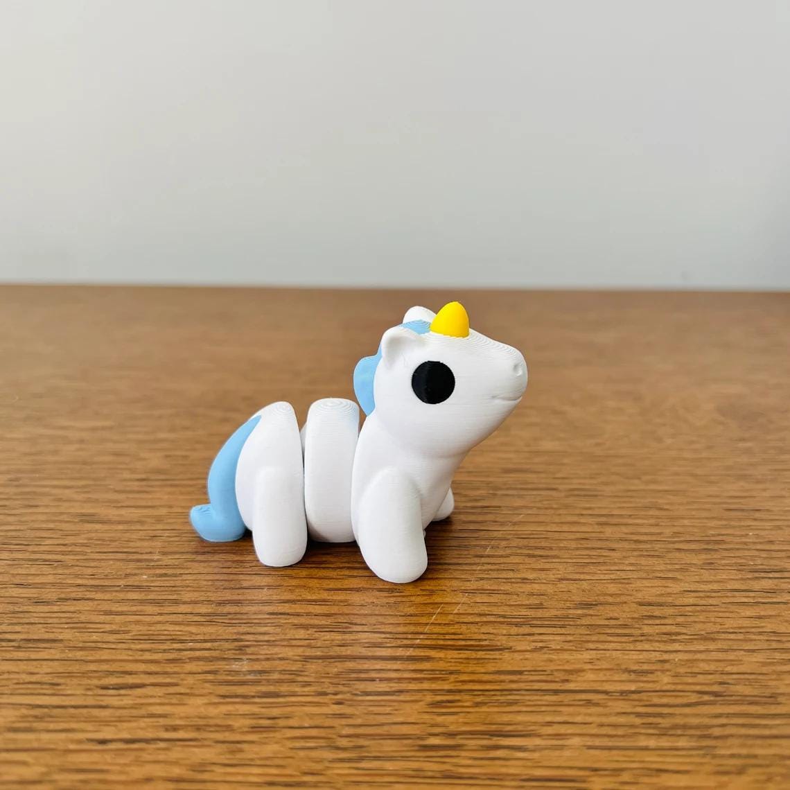A charming blue and white articulated unicorn with a golden horn, perfect for sensory play and stress relief.