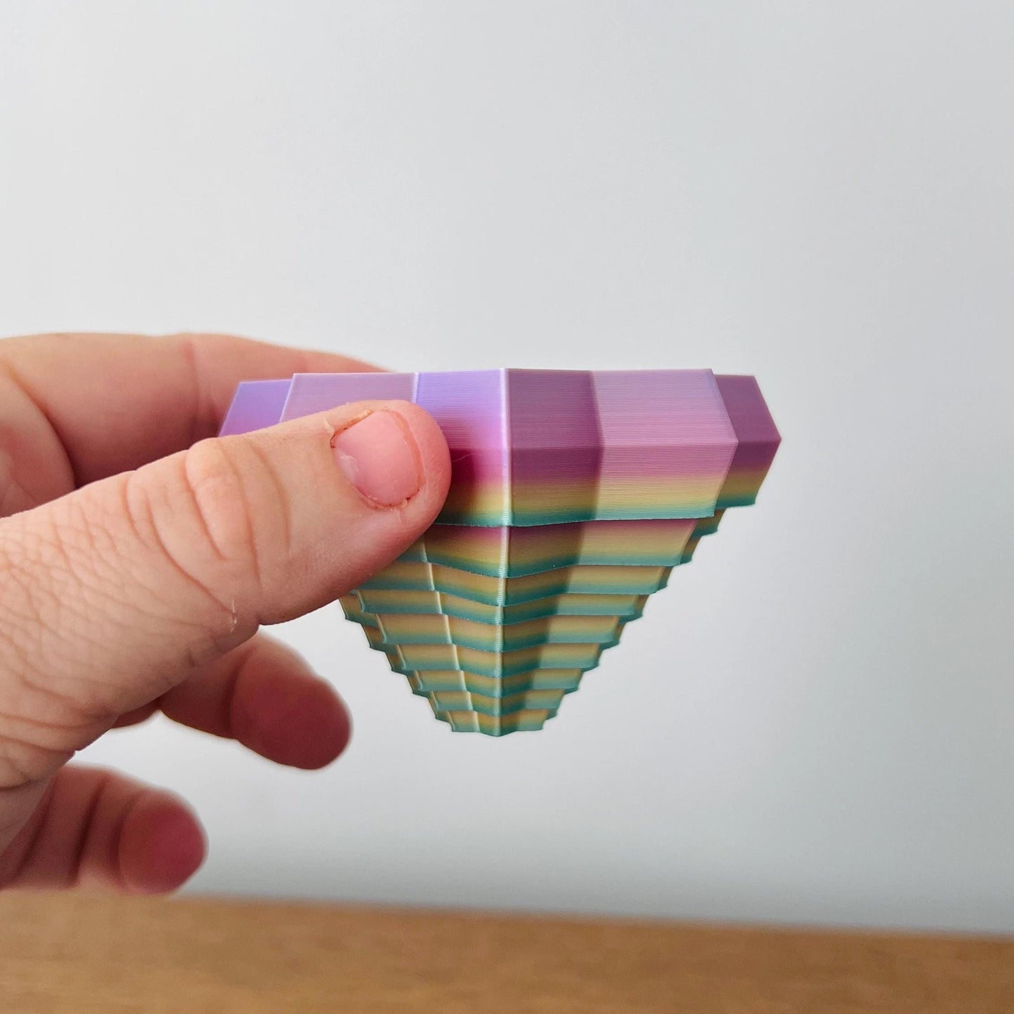 A hand holds a colorful, star-shaped fidget with vibrant, layered hues and unique patterns, creating a captivating tactile ex
