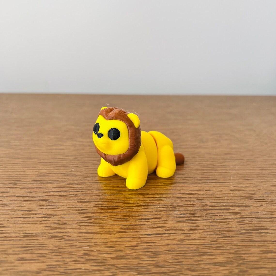 Bright yellow articulated lion with a brown mane, perfect for sensory play and stress relief on a wooden surface.