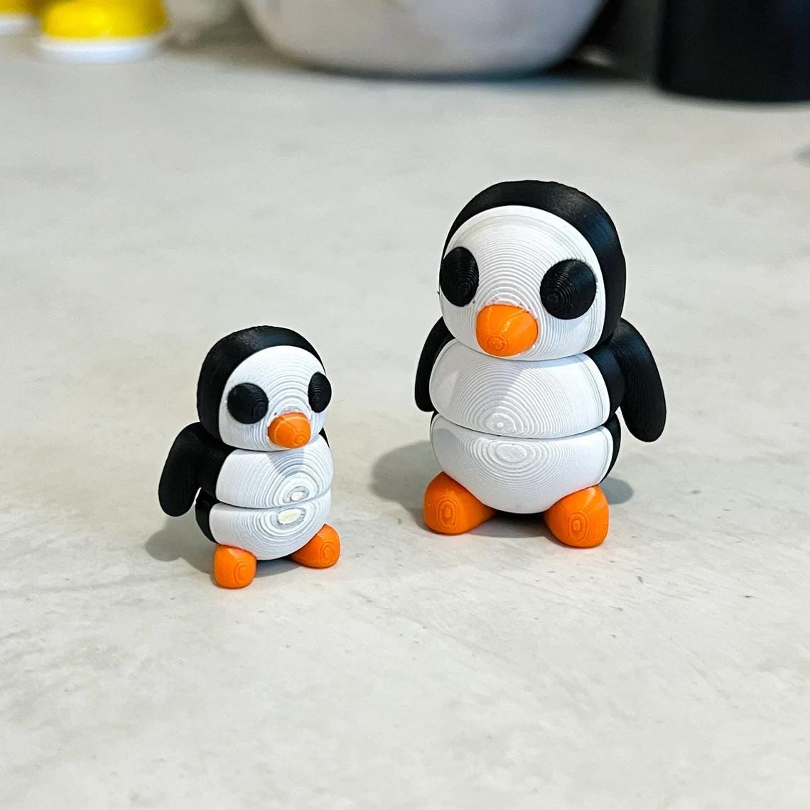 Two charming, articulated penguins in black and white with orange accents, perfect for sensory play and stress relief.
