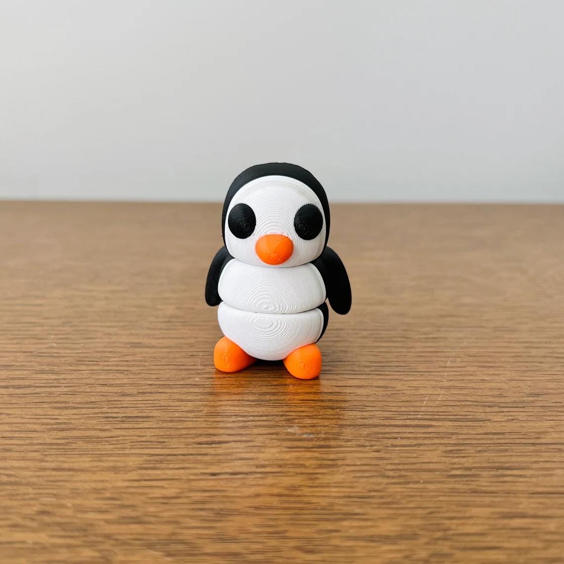 Charming 3D printed penguin with articulated body, featuring black and white colors and orange accents, perfect for fidgeting