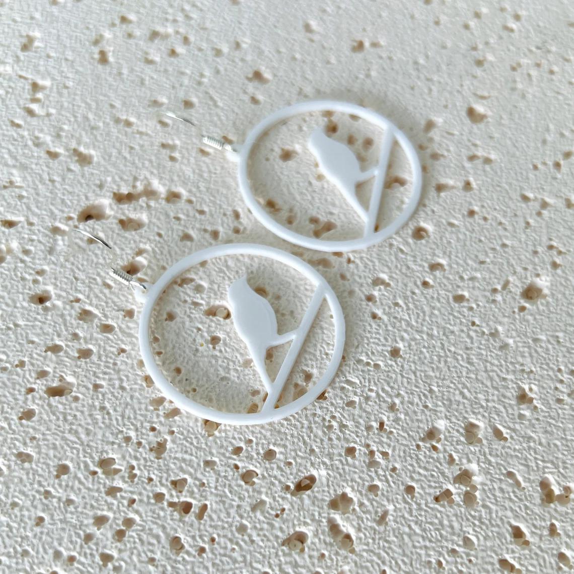 White bird dangle earrings feature a delicate design, crafted from lightweight plastic with sterling silver hooks.
