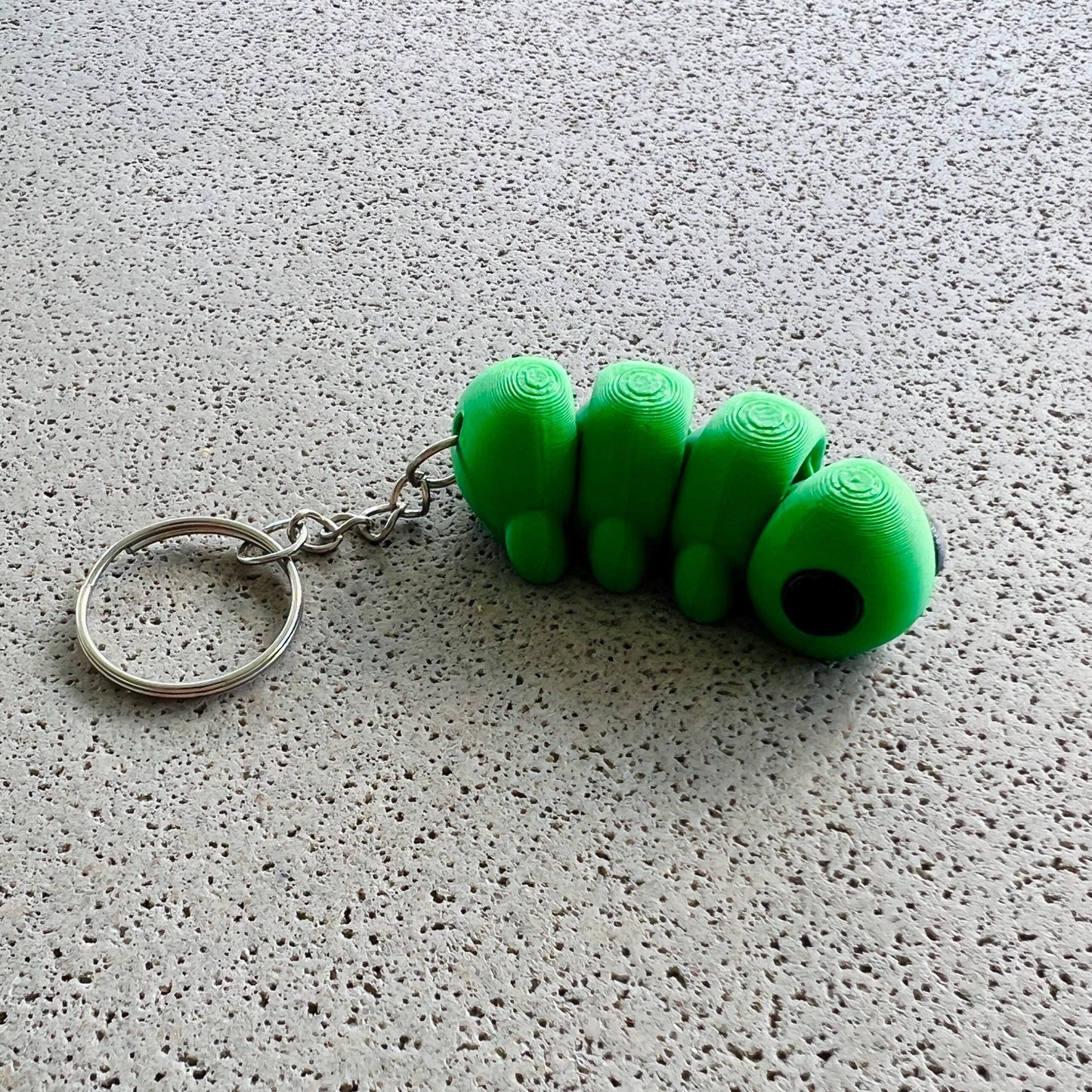 Whimsical green caterpillar keychain with detailed segments, perfect for adding charm to keys or bags.