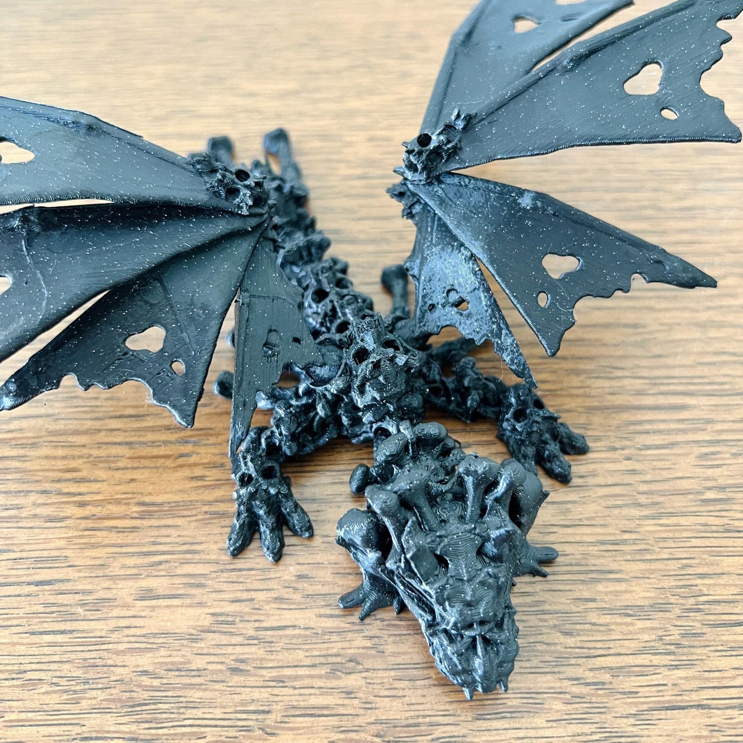 A striking black dragon with skull-like features and hollow, heart-shaped wings, exuding a mystical, edgy vibe.