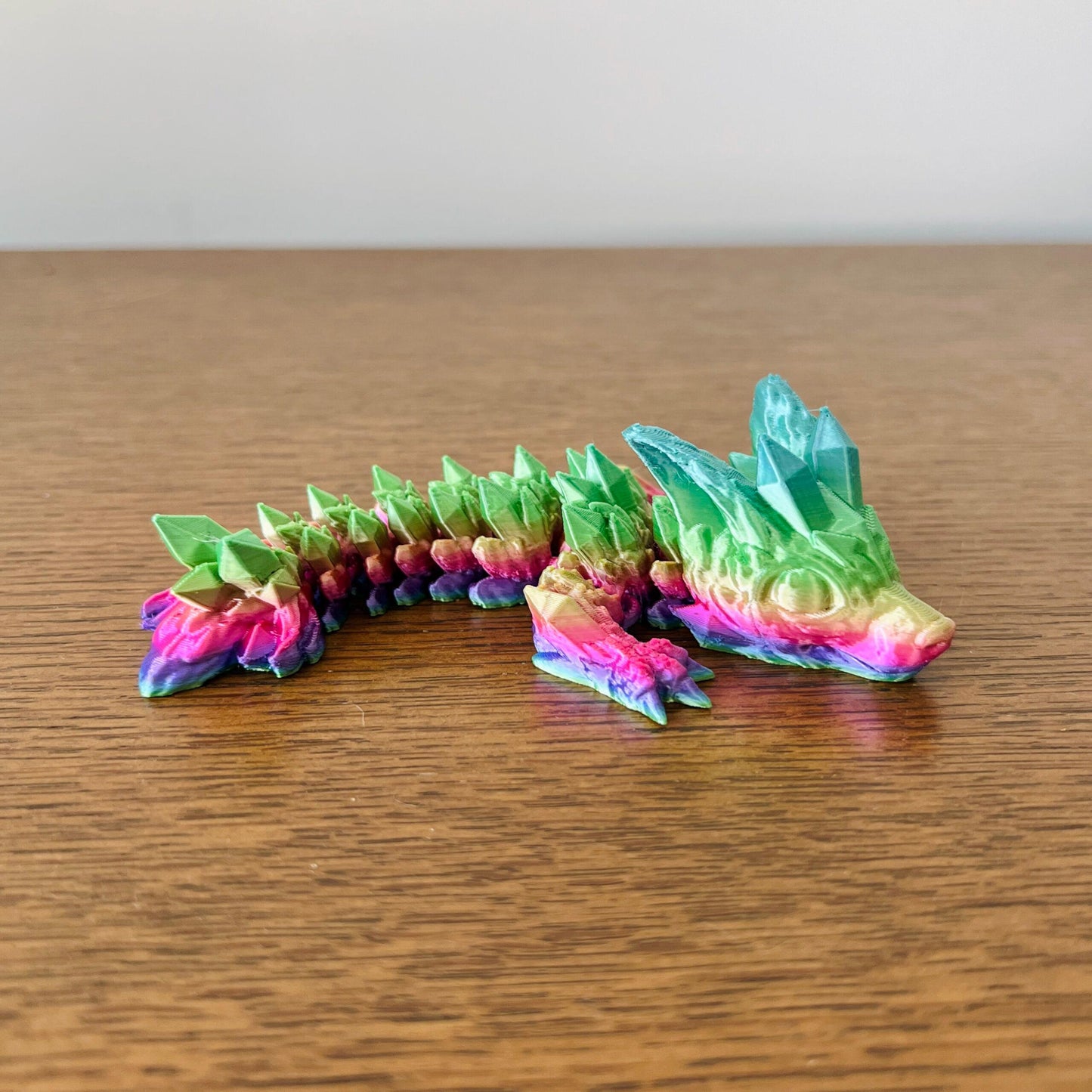 Vibrant, wingless dragon with crystal-like accents in green, pink, and blue, exuding a mystical, fierce elegance.