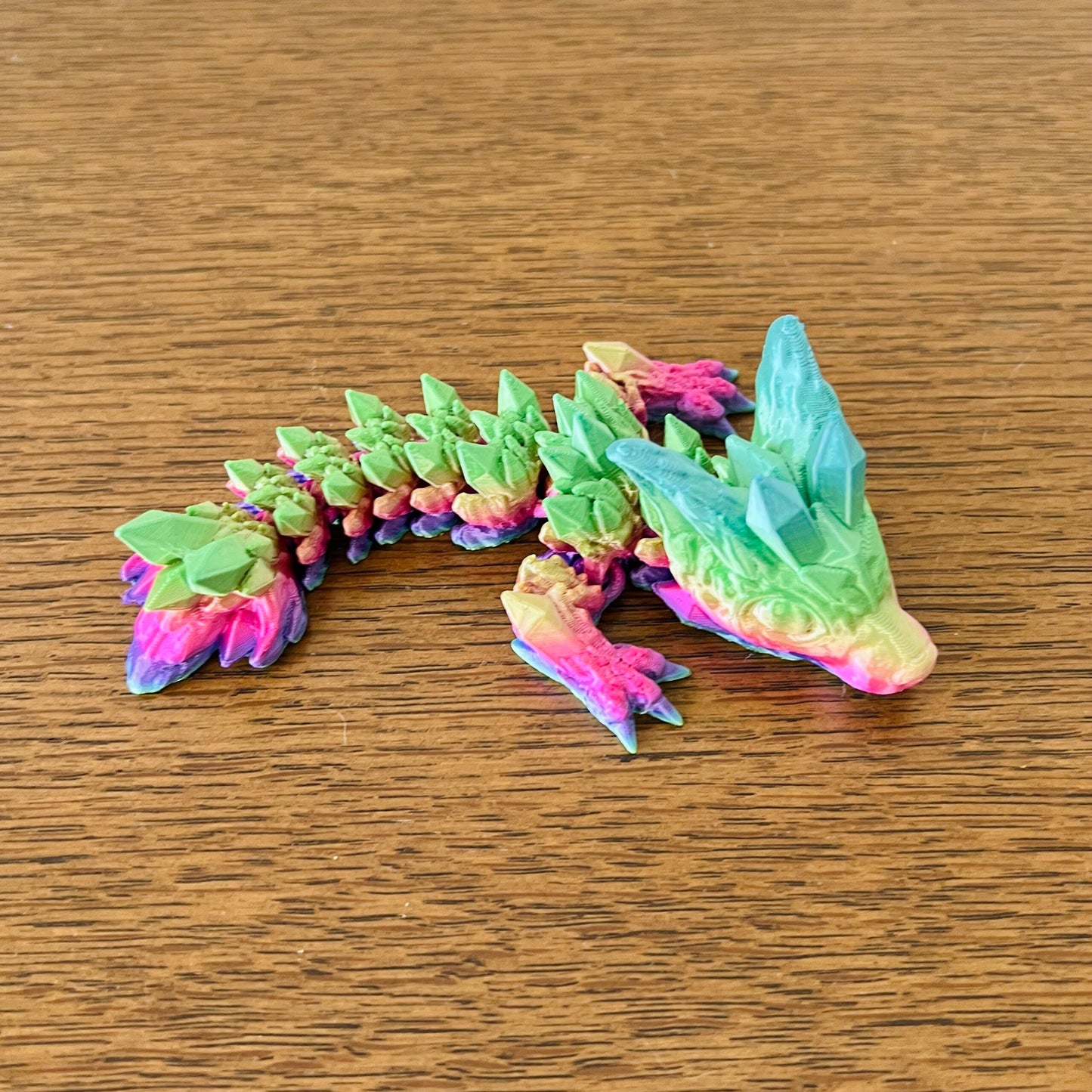 Colorful wingless dragon with crystal accents, showcasing fierce elegance in vibrant hues of green, pink, and blue.