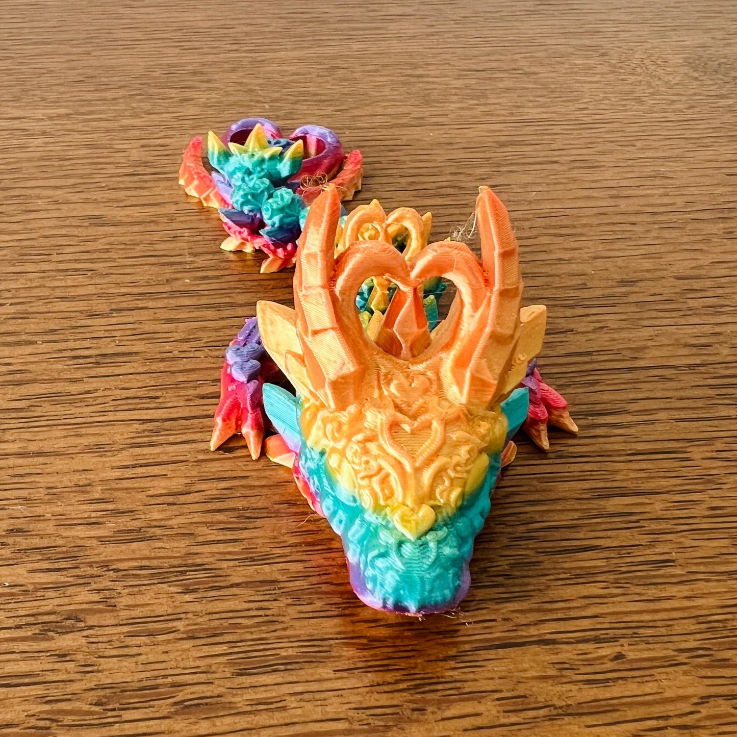 Colorful, wingless dragon with heart-shaped details, showcasing an edgy, elegant design and captivating dark hues.