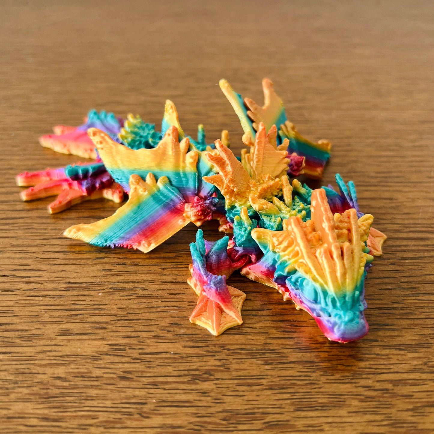 Colorful dragon with wave-like details and vibrant hues inspired by the ocean, resting on a wooden surface.