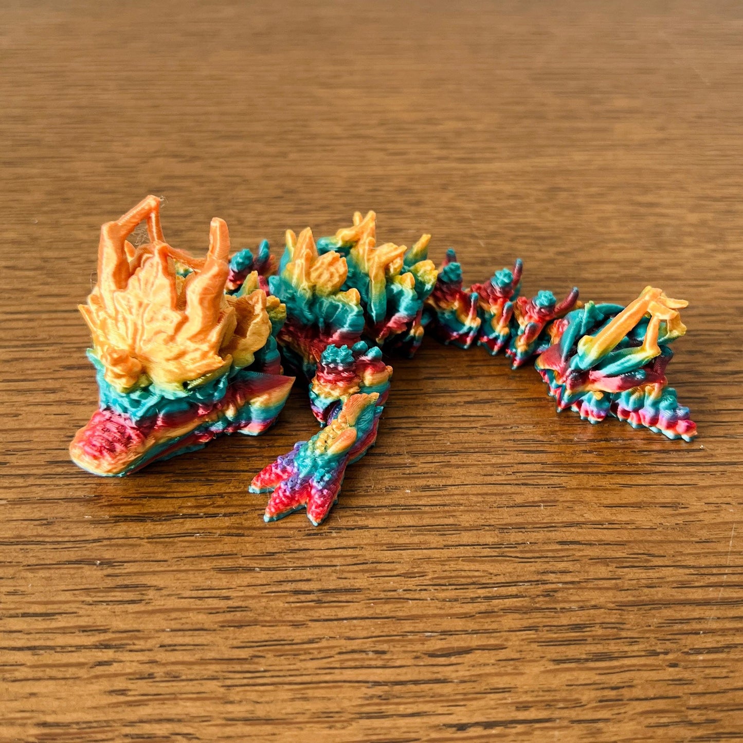 Colorful, textured dragon inspired by autumn leaves, featuring vibrant hues and intricate details throughout its form.