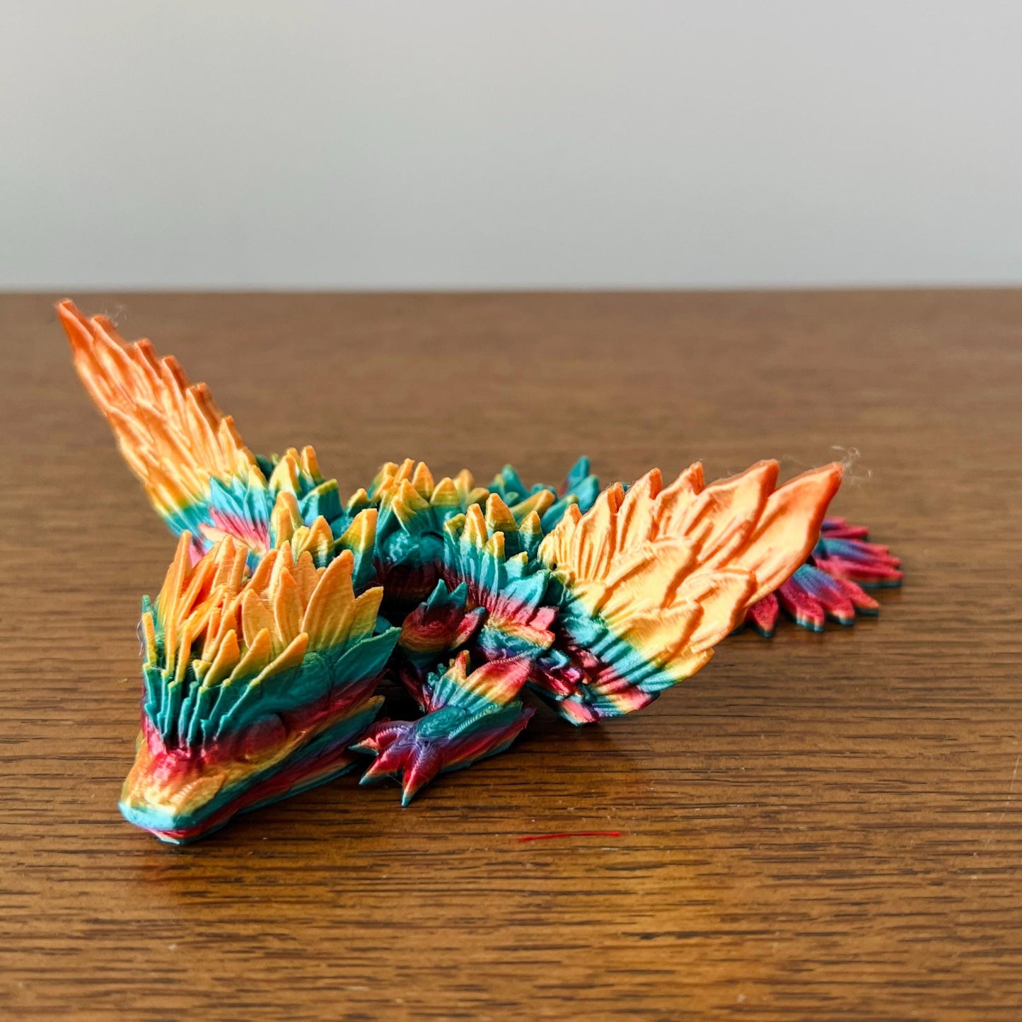 Colorful winged dragon with sunflower-inspired details, showcasing vibrant hues of orange, teal, and yellow.