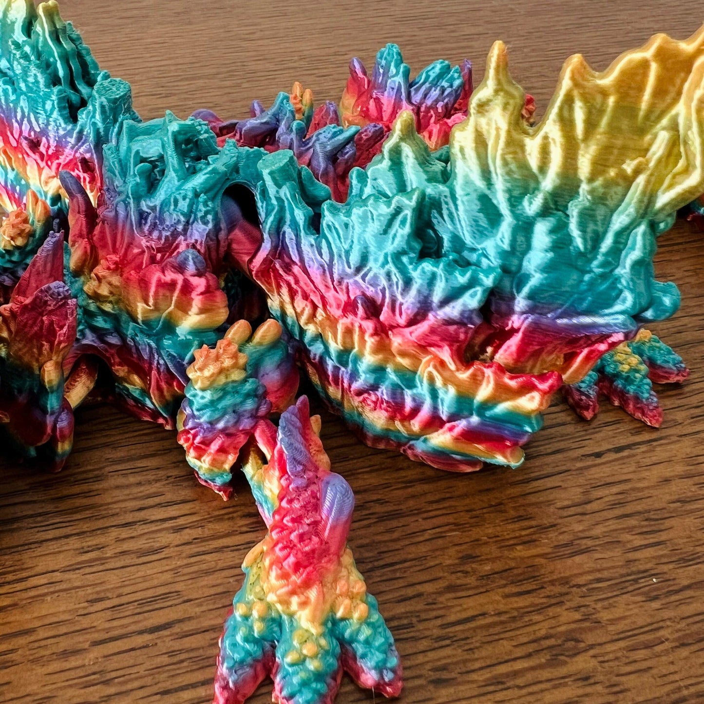 Colorful dragon with intricate wings, showcasing vibrant autumn hues of red, orange, and teal, resembling fall leaves.