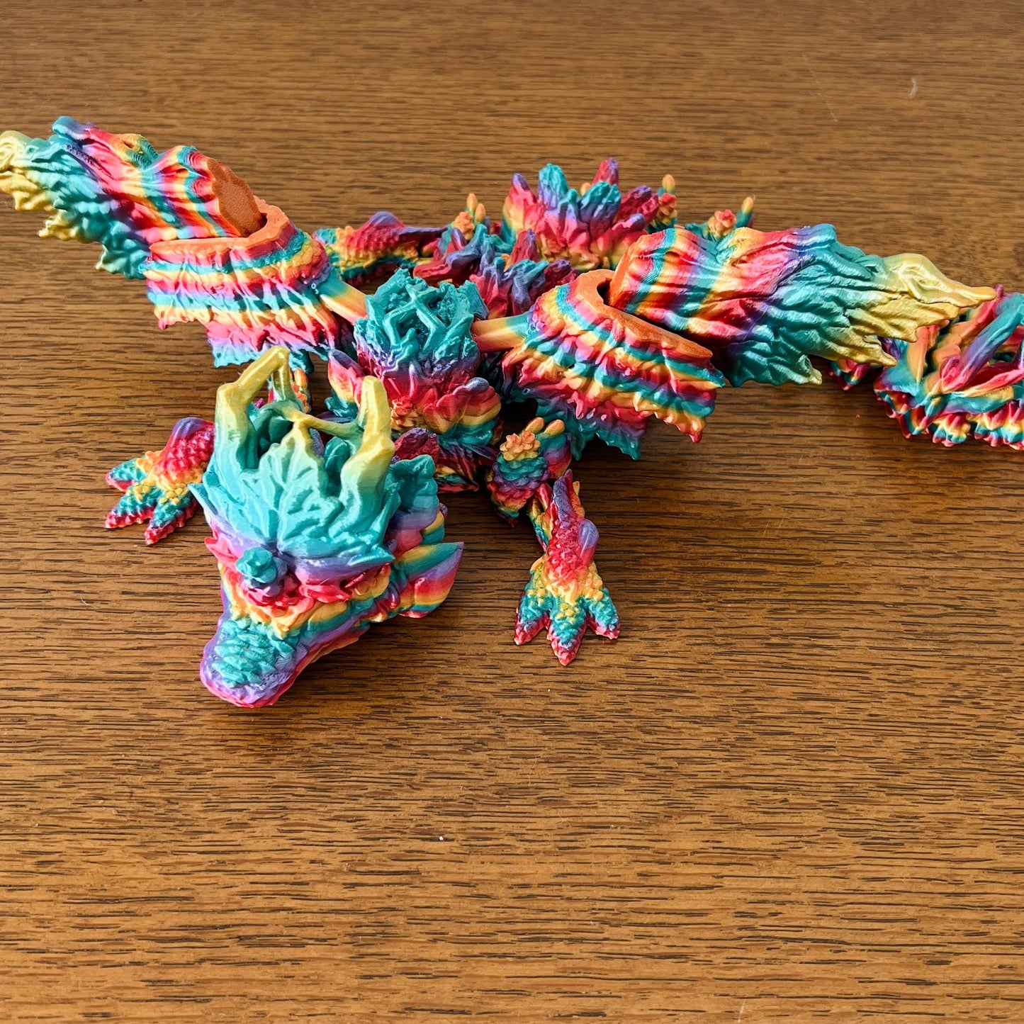 Colorful dragon with intricate wings and details reflecting autumn leaves, showcasing vibrant hues of red, orange, and teal.