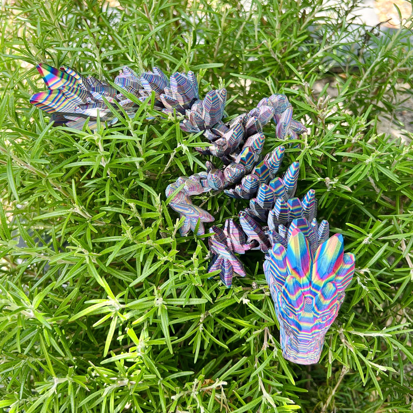 Colorful gemstone-inspired dragon with intricate details nestled among vibrant green foliage.
