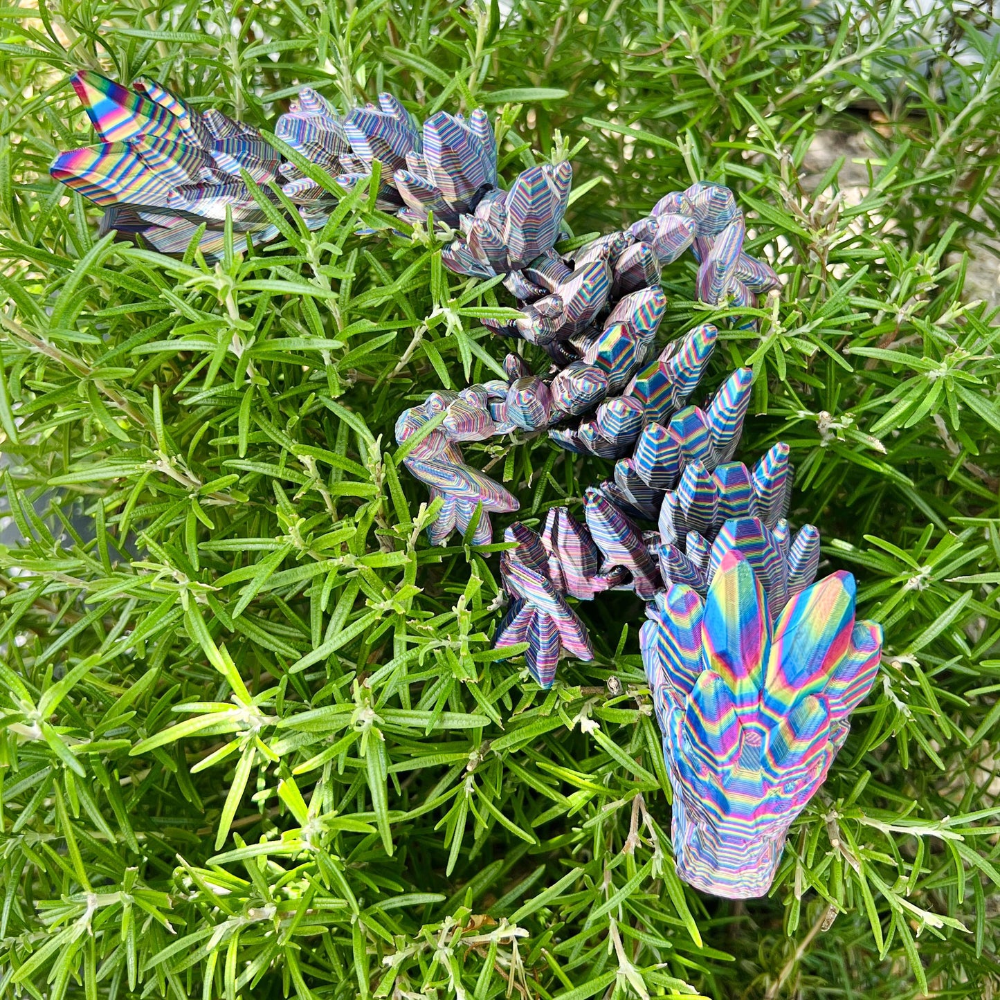 A colorful, intricately detailed dragon resembling precious gemstones rests among vibrant green foliage.