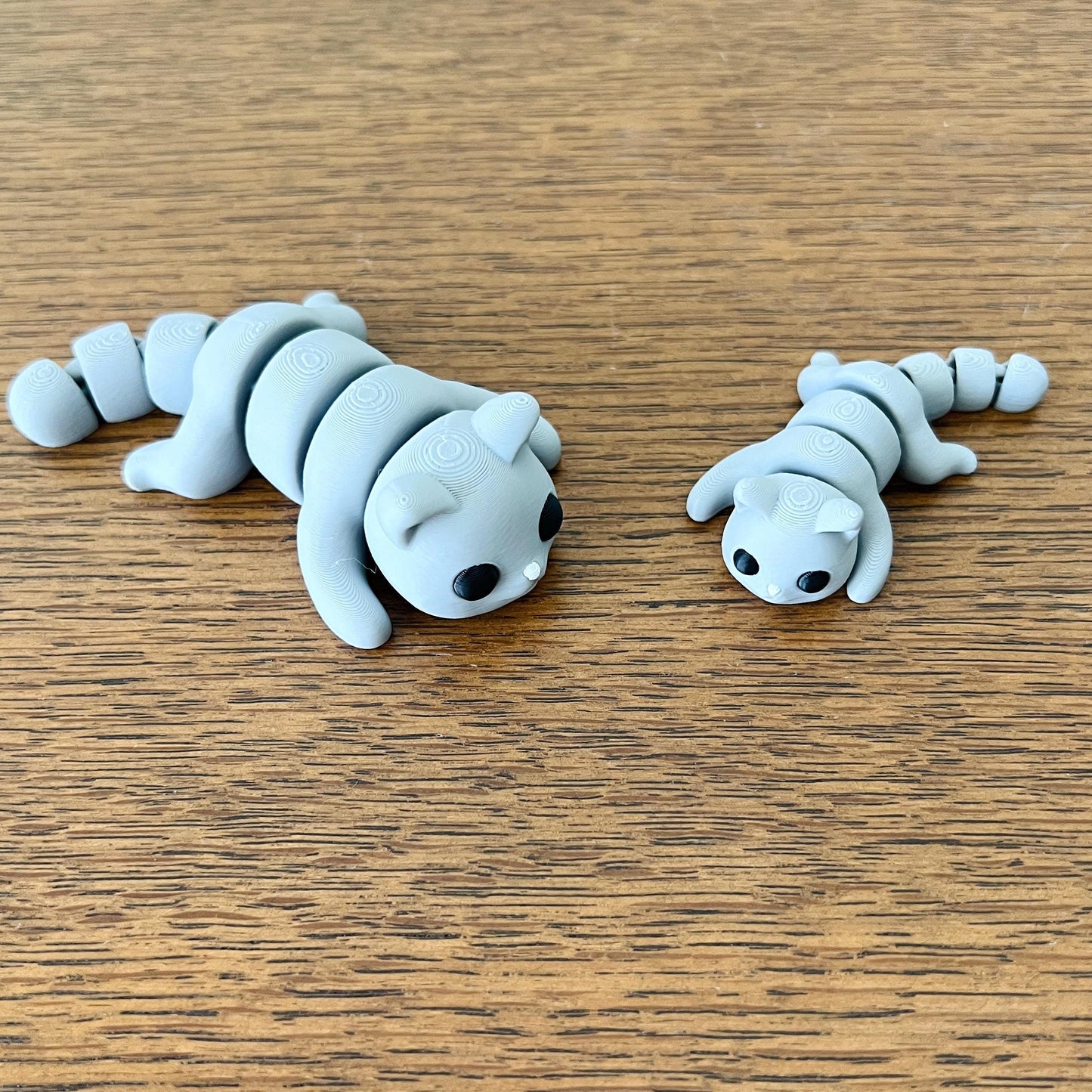 Two articulated grey cats in a playful pose on a wooden surface, perfect for tactile enjoyment and stress relief.