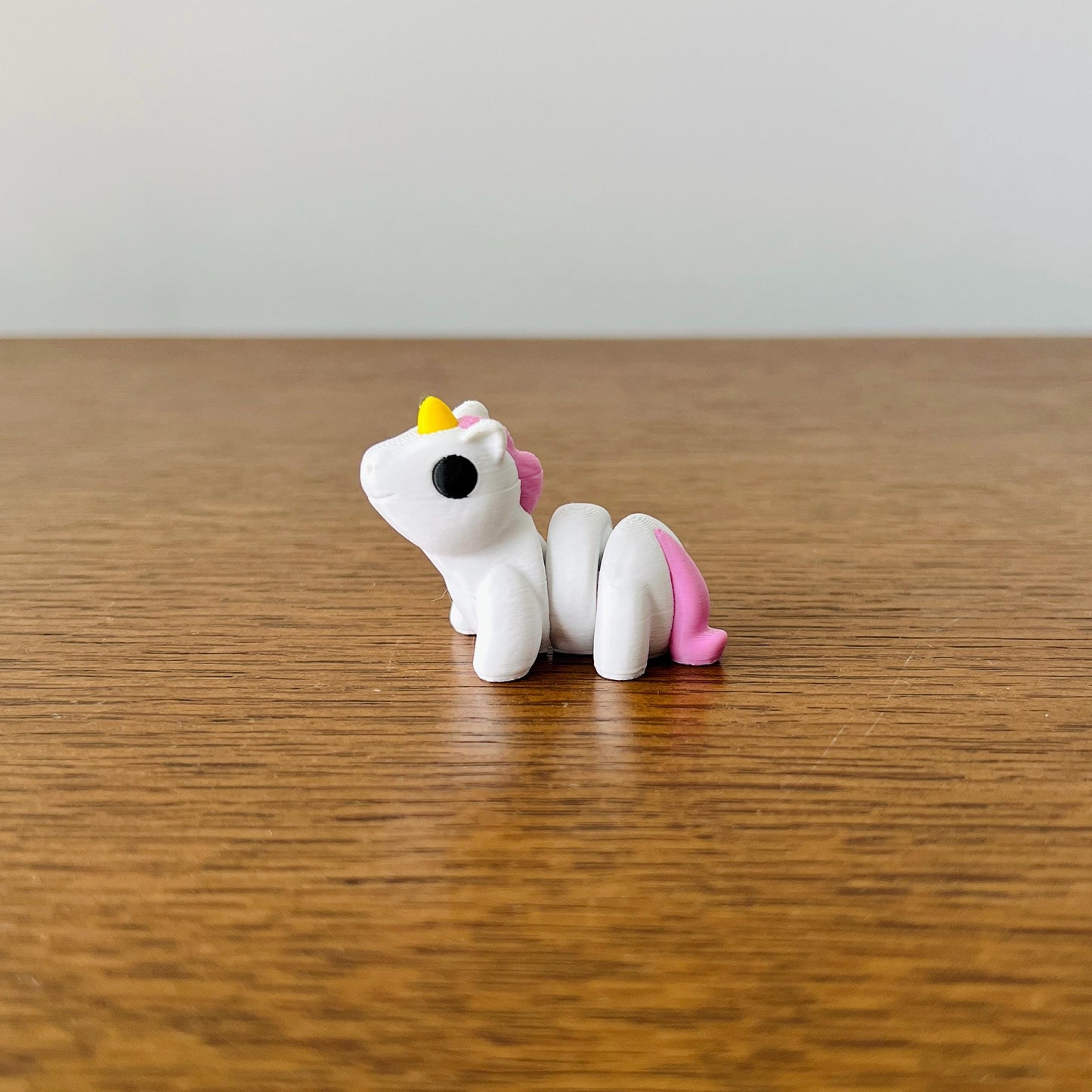 Adorable articulated unicorn with a white body, yellow horn, and pink mane, perfect for sensory play and collection.