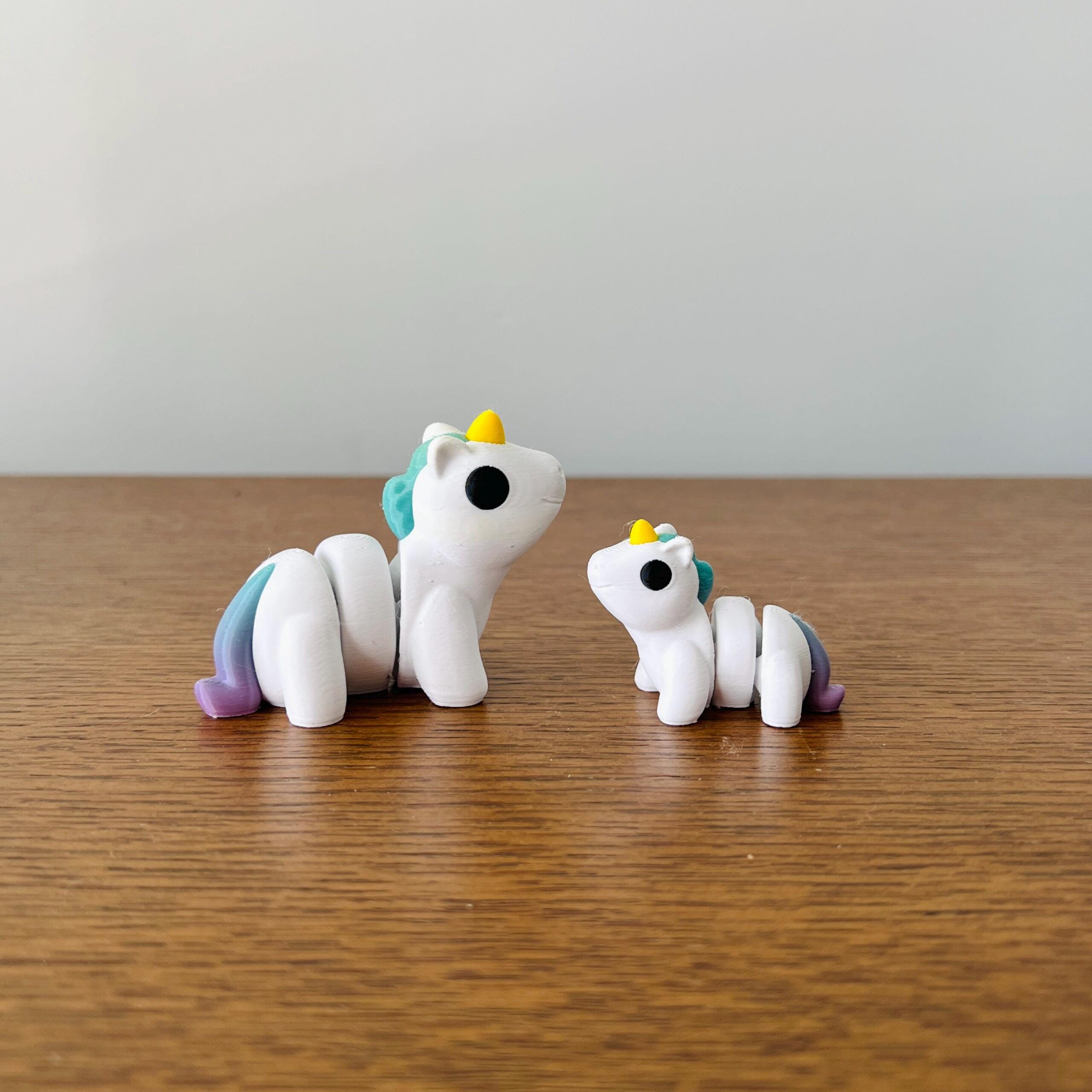 Two playful white unicorns, one larger and one smaller, with vibrant rainbow manes and cheerful expressions.