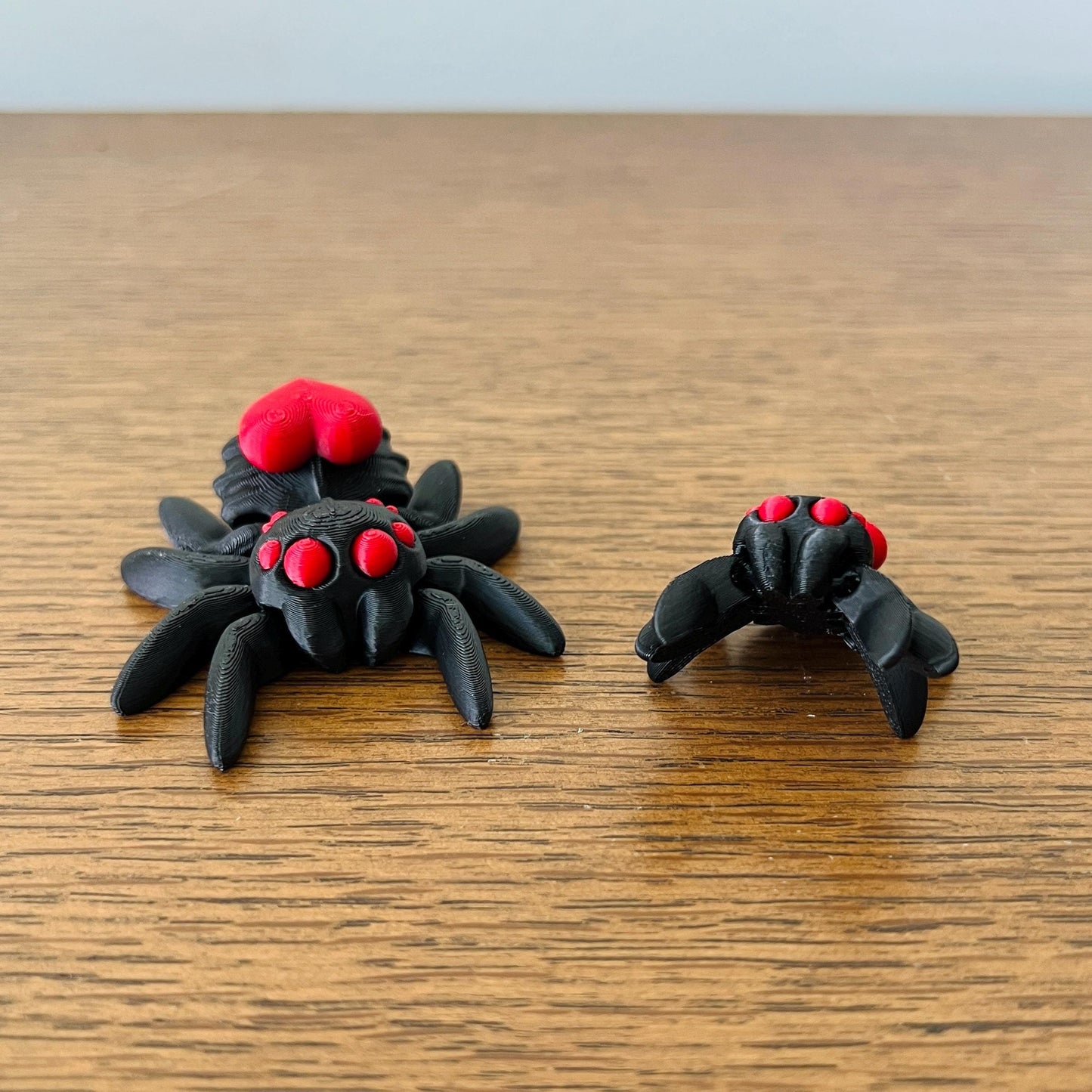 3D printed black spider figures with a vibrant red heart and eyes, showcasing a charming and quirky design.