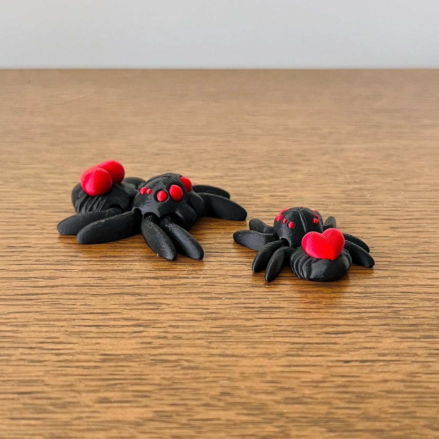 Adorable black spiders with red hearts on their backs, adding charm to any fidget collection.
