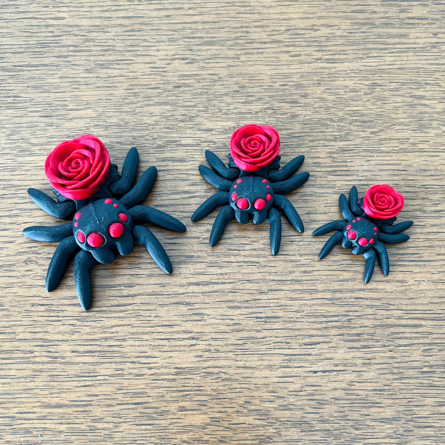 A trio of black spiders adorned with delicate red roses, showcasing a blend of gothic charm and playful elegance.