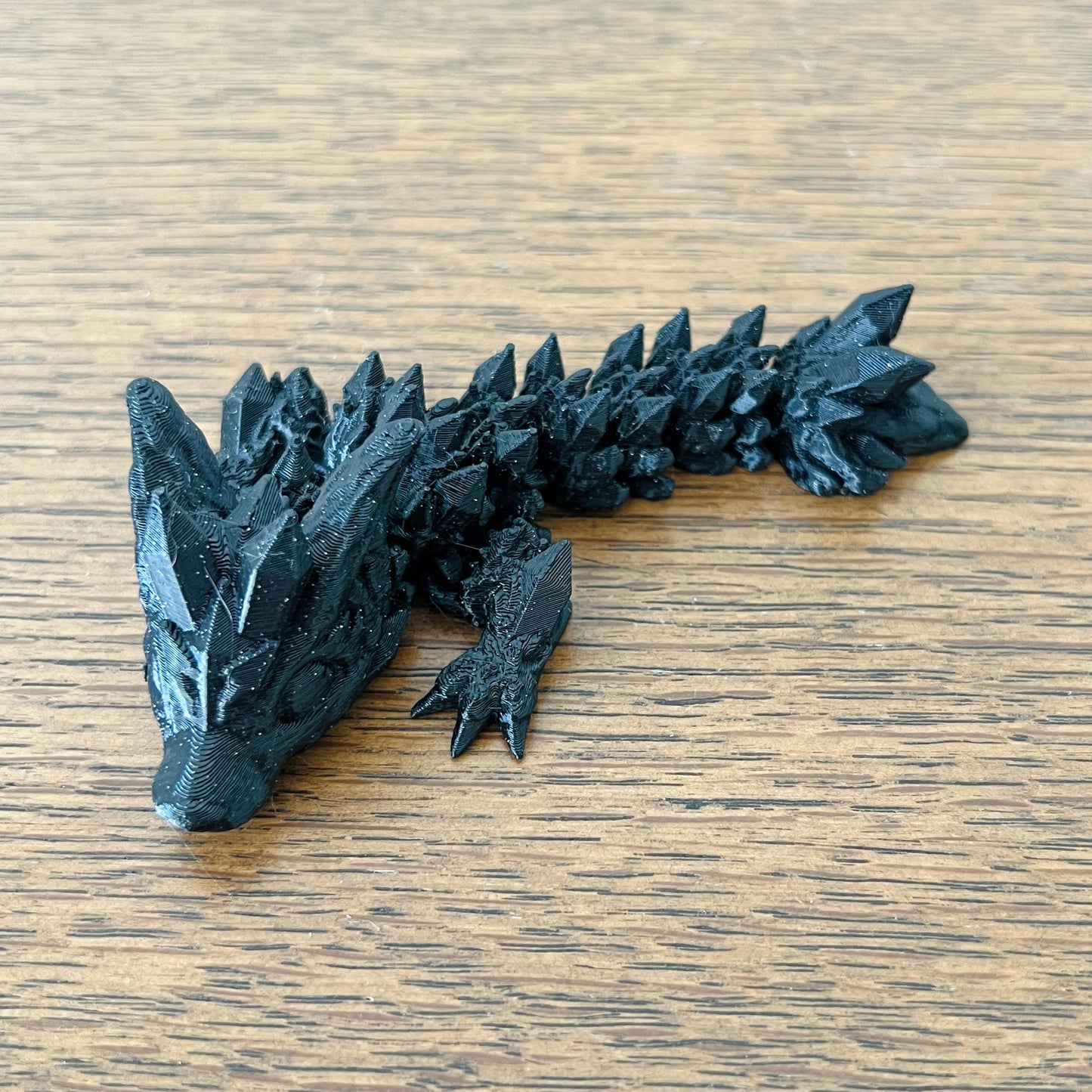 Intricate black figure blends wolf and dragon features, showcasing sharp spikes and a captivating, mystical presence.
