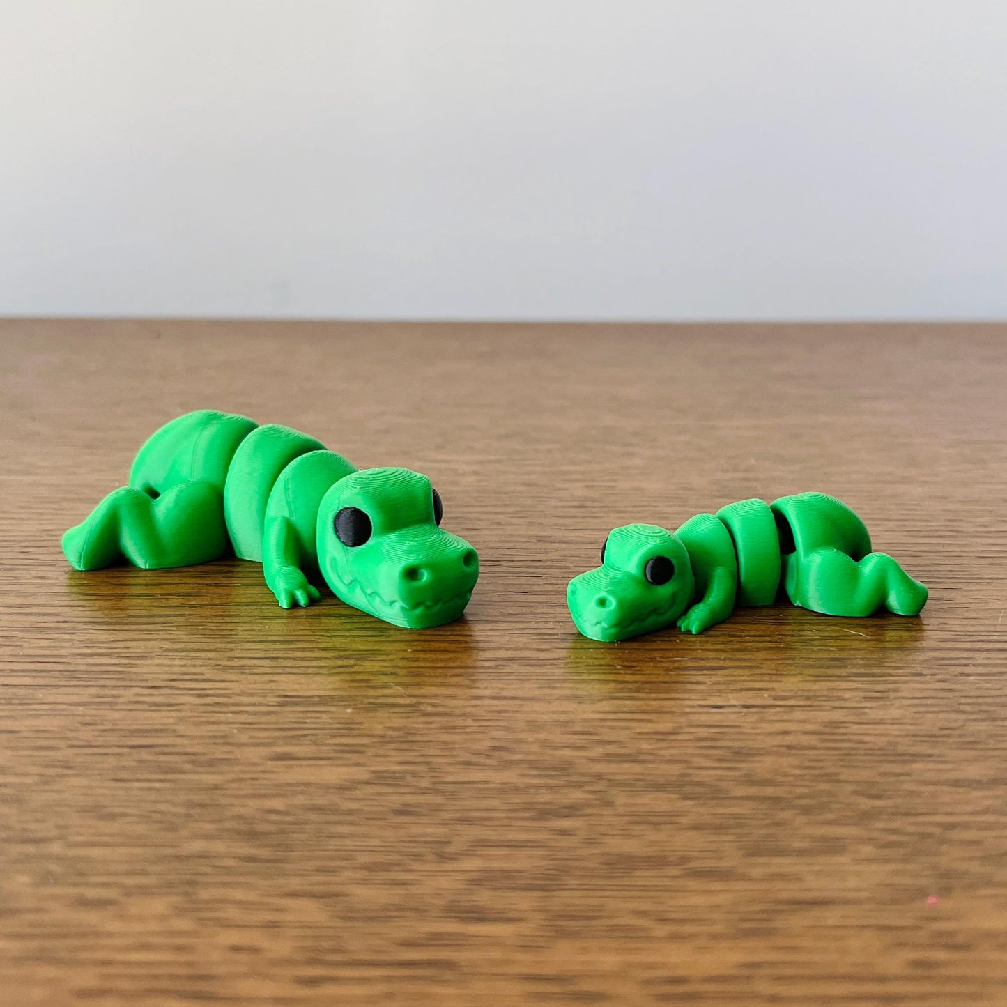 Bright green miniature T-Rex figures, showcasing intricate details, lying on a wooden surface. Perfect for dinosaur enthusias
