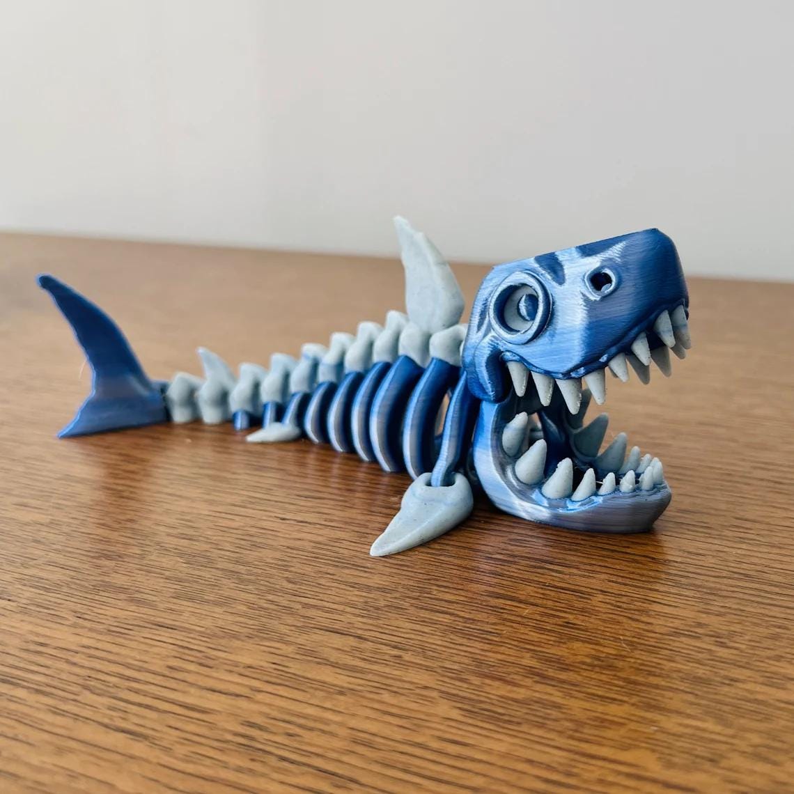 3D-printed skeleton shark figurine in blue, showcasing detailed teeth and fins, perfect for ocean-inspired decor.