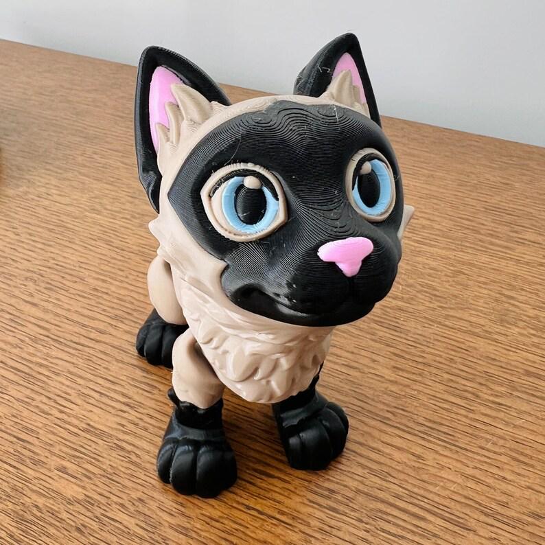 Charming 3D-printed Siamese cat figurine with bright blue eyes, pink accents, and a sleek design, perfect for cat lovers.
