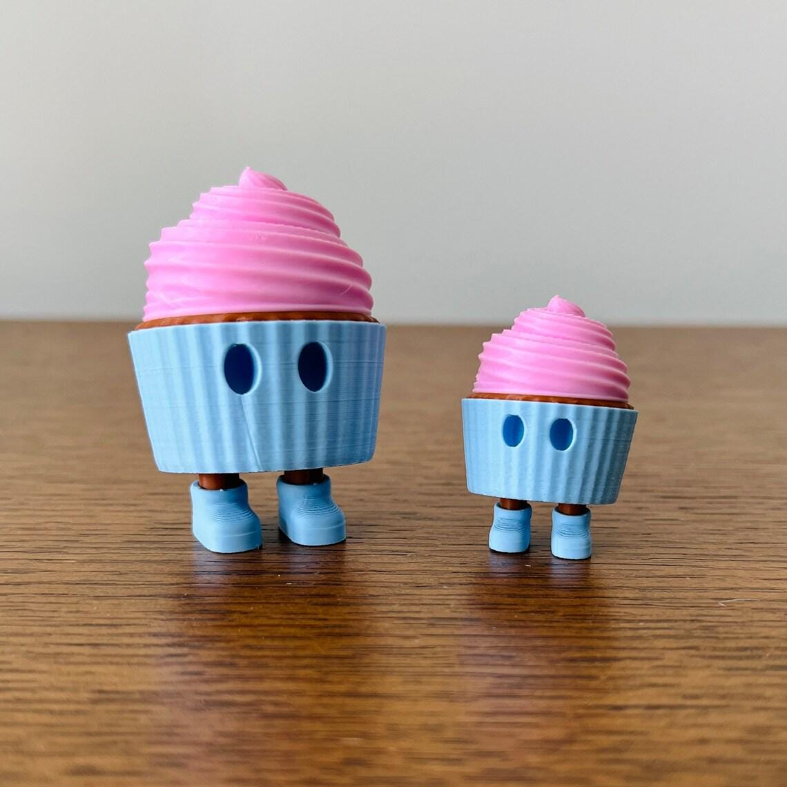 Adorable 3D printed mini cupcakes with pink frosting, playful eyes, and movable legs, perfect for sensory fun.