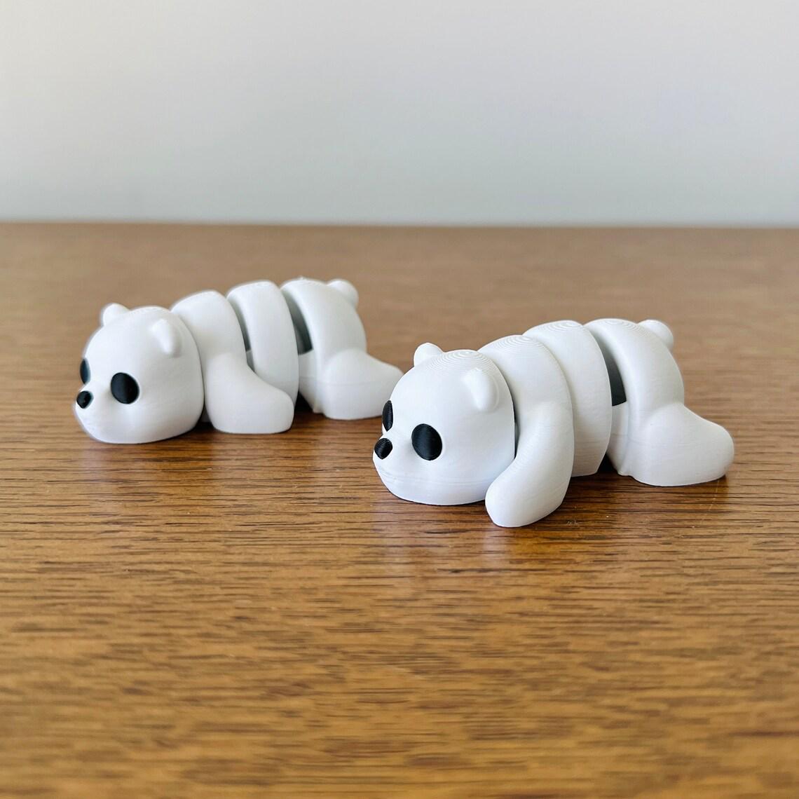 Two adorable articulated white bears with black eyes, resting on a wooden surface, showcasing their charming design.