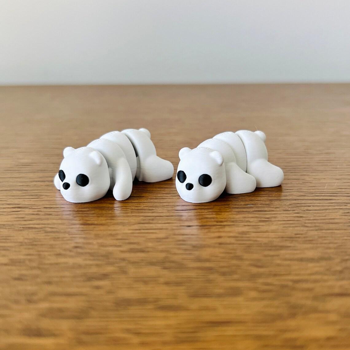 Two adorable white polar bears with black eyes, lying on a wooden surface, showcasing their articulated features.