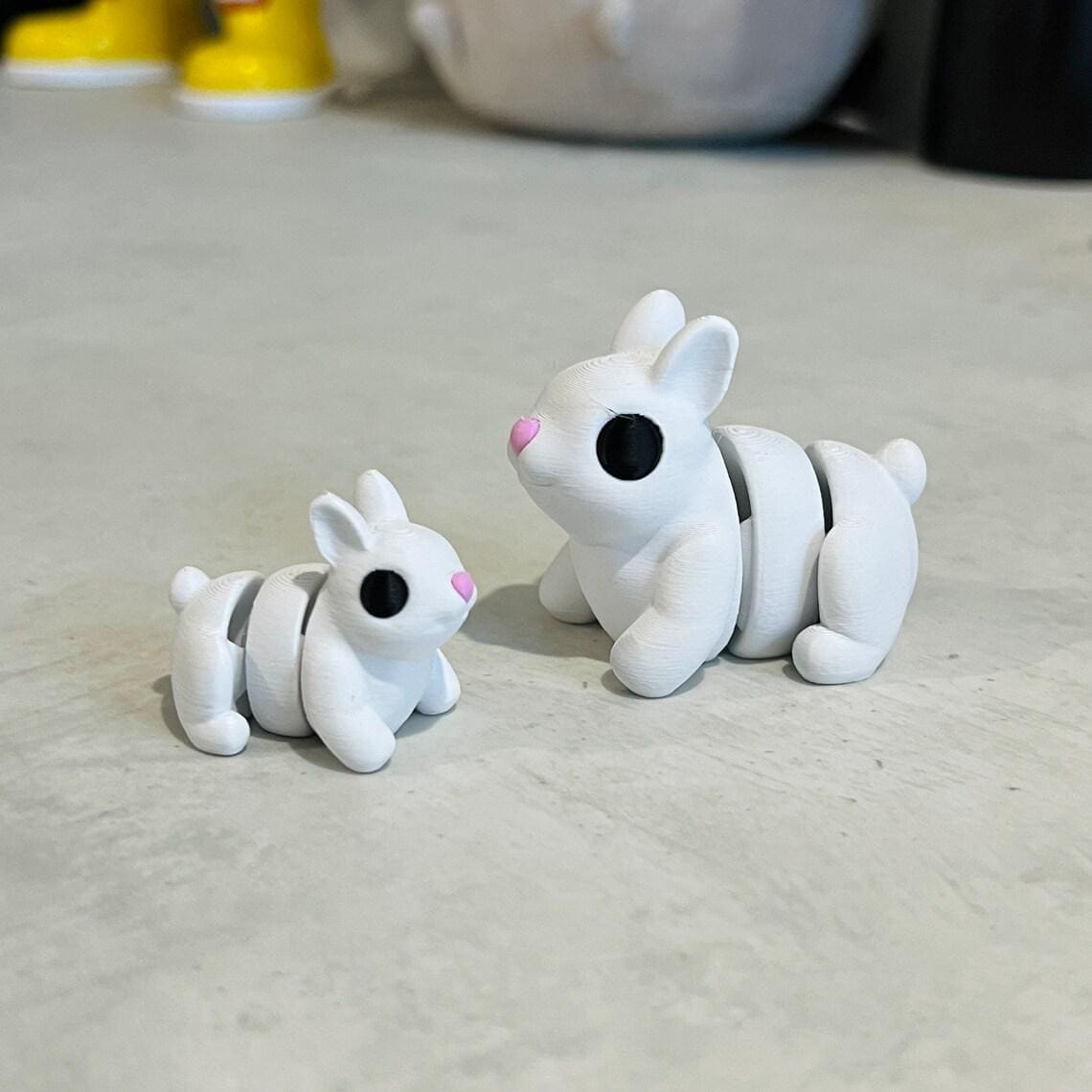 Two articulated bunny rabbits in white with black eyes and pink noses, designed for sensory play and stress relief.